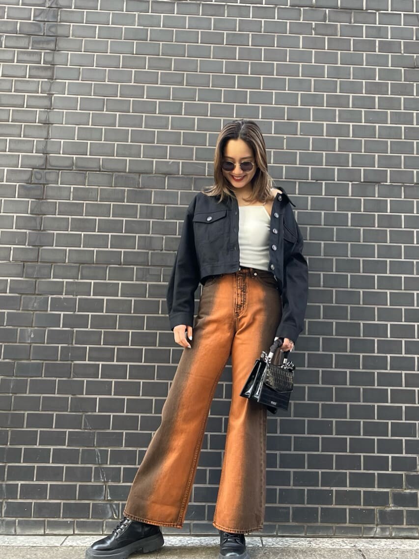 ブラック系のブルゾン、ブラック系のブーツ、ホワイト系のキャミソールを着用したレディースの春コーディネートの3枚目の写真