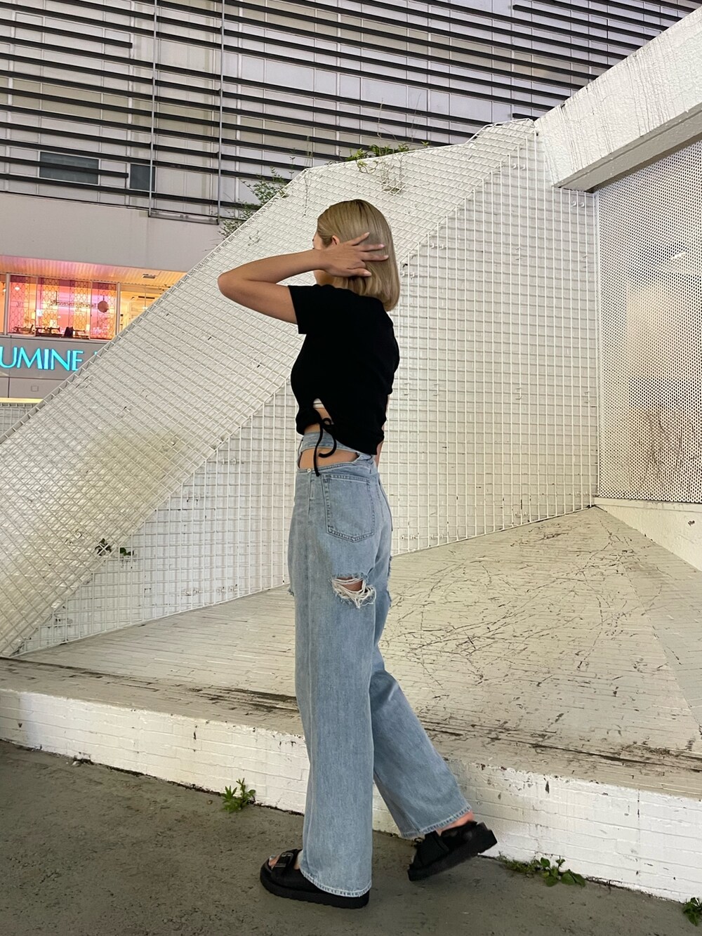 ブルー系のデニムパンツ、ブラック系のTシャツ/カットソー、ブラック系のサンダルを着用したレディースの夏コーディネートの3枚目の写真