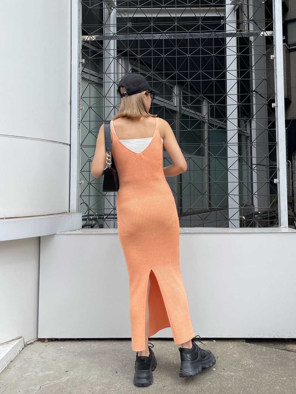 オレンジ系のワンピース、ブラック系のハンドバッグを着用したレディースの春コーディネートの5枚目の写真