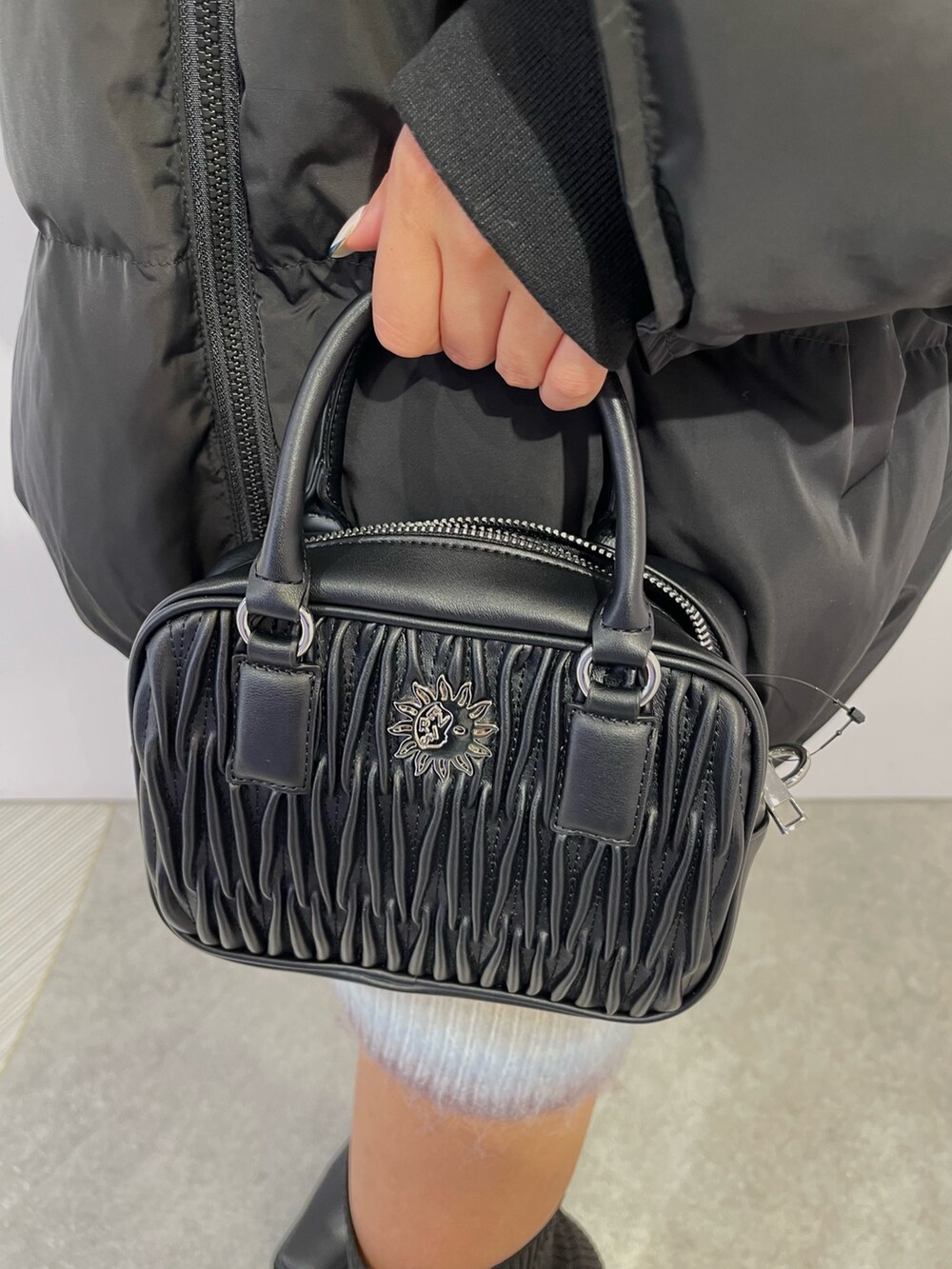 パープル系のニット/セーター、ブラック系のブーツ、ブラック系のダウンジャケット/コートを着用したレディースの冬コーディネートの8枚目の写真