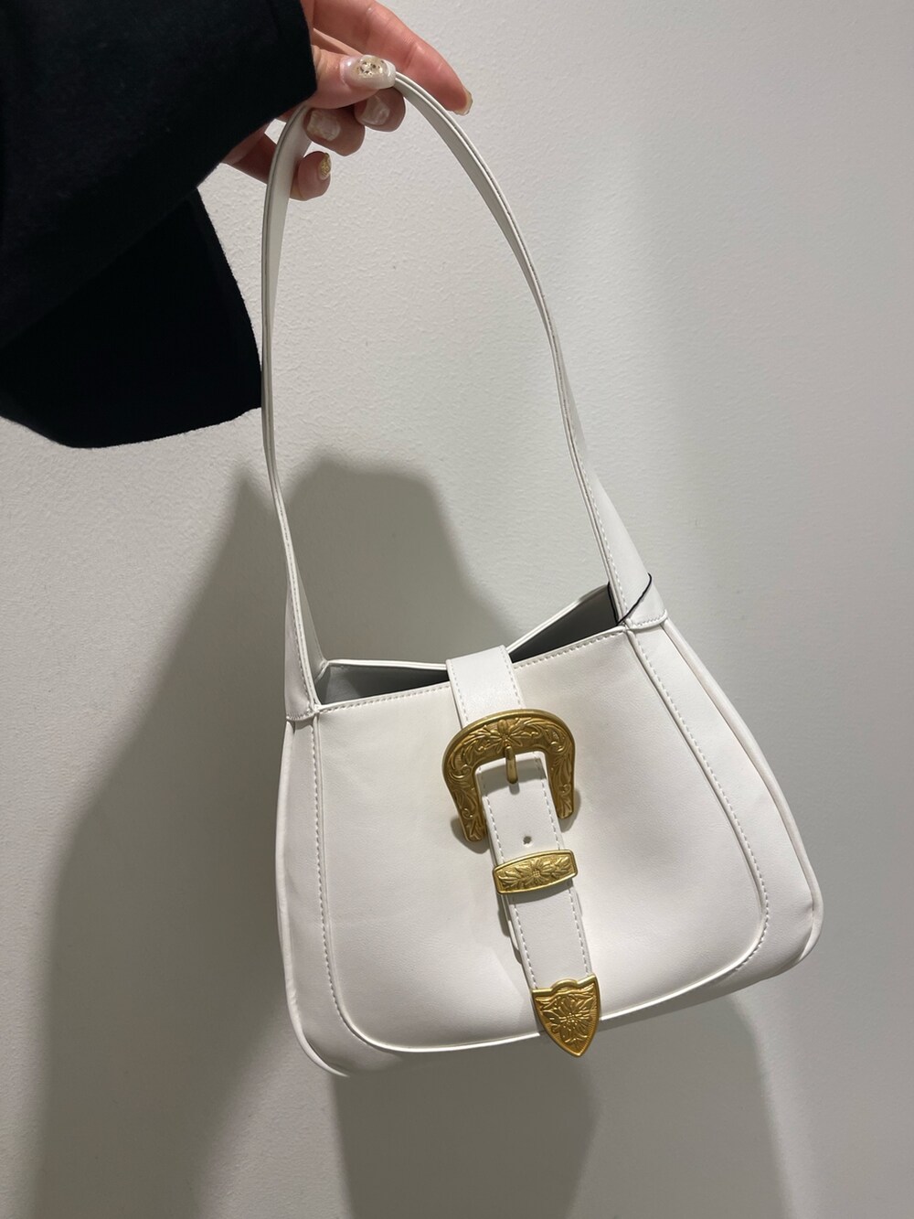 ホワイト系のブーツ、ブラック系のハンドバッグ、ブラック系のワンピースを着用したレディースの冬コーディネートの7枚目の写真