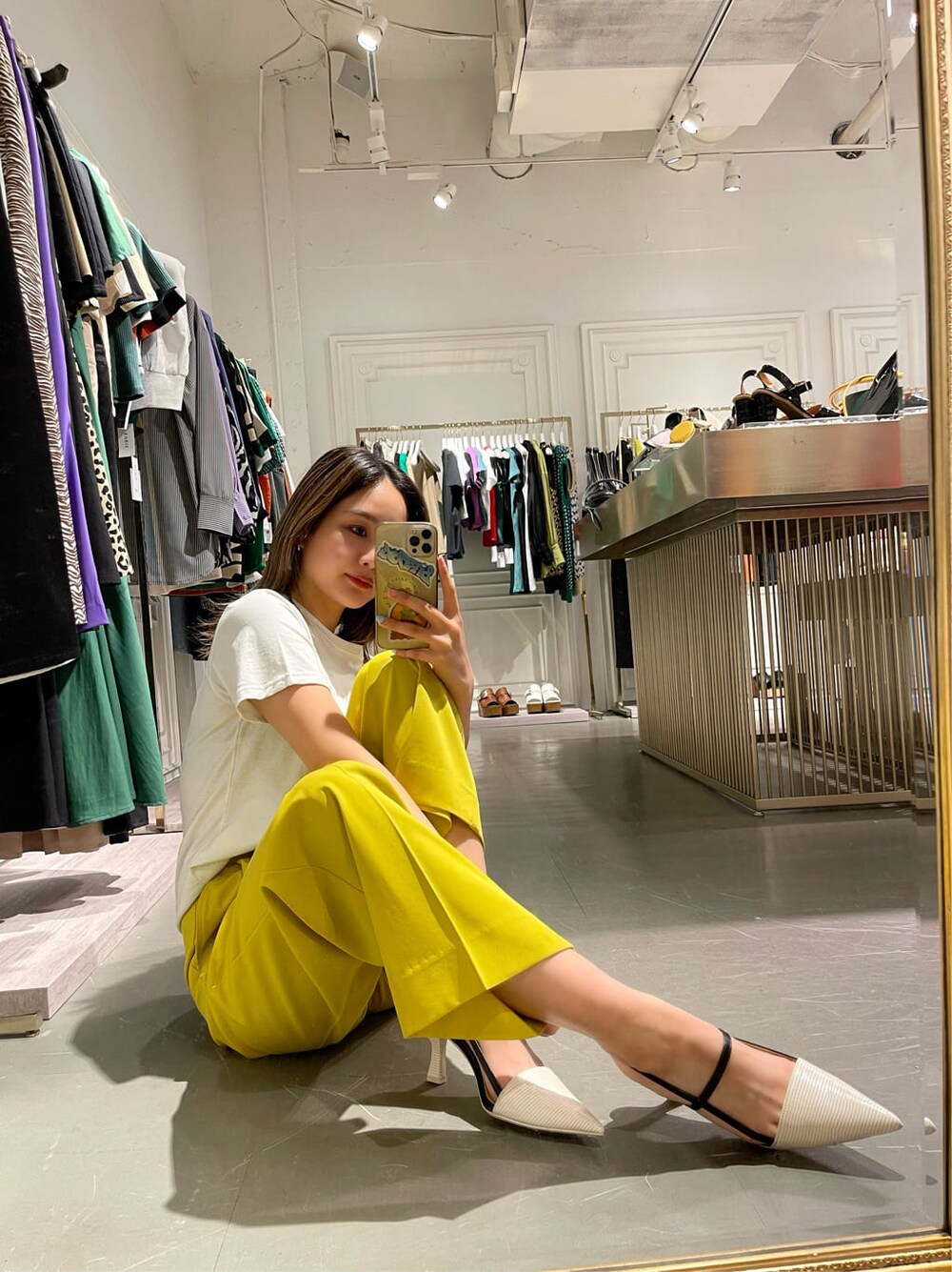 イエロー系のスラックス、ホワイト系のTシャツ/カットソー、ホワイト系のサンダルを着用したレディースの春コーディネートの6枚目の写真