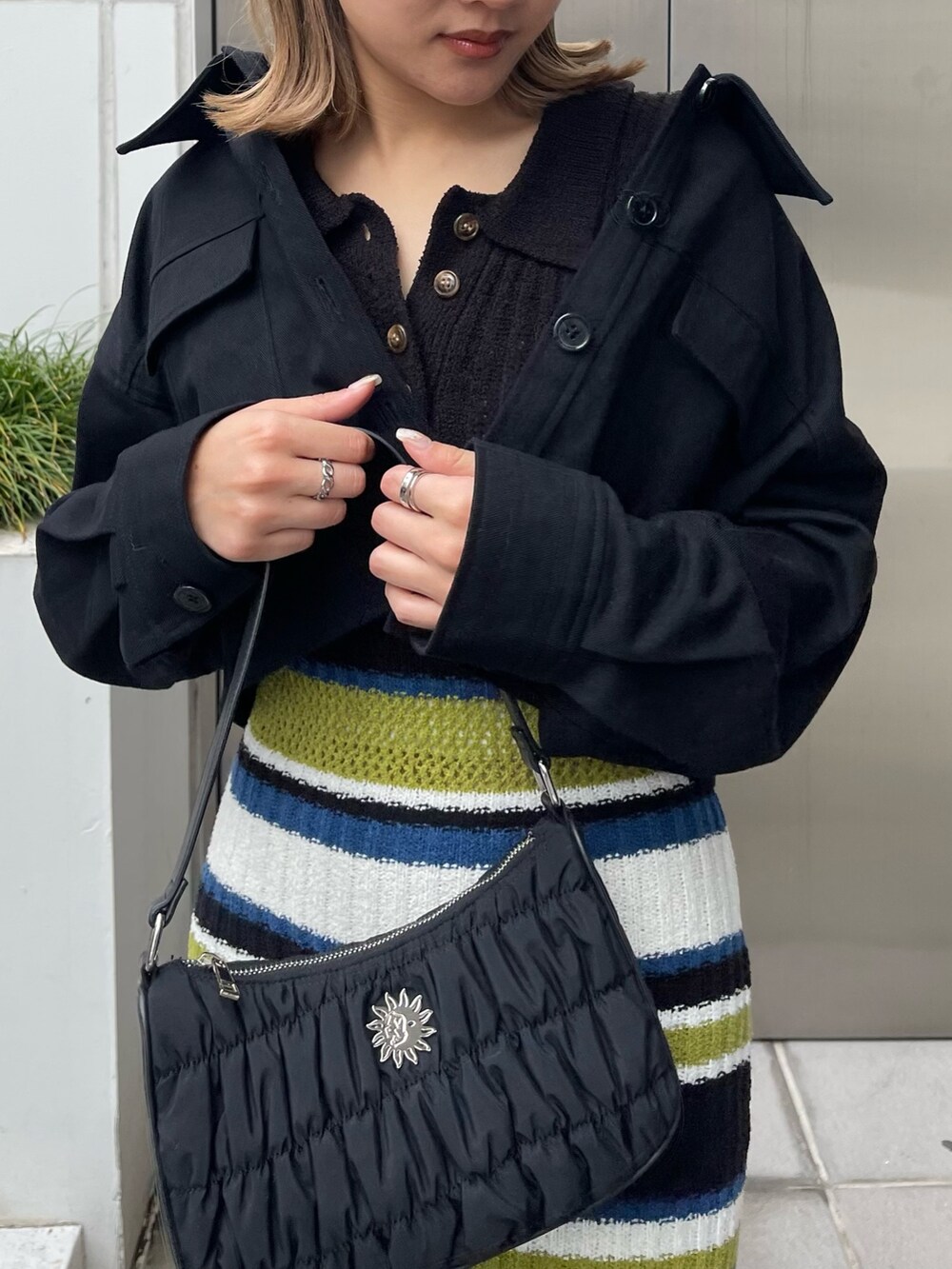 ブラック系のワンピース、ブラック系のミリタリージャケット、ブラック系のハンドバッグを着用したレディースの春コーディネートの6枚目の写真