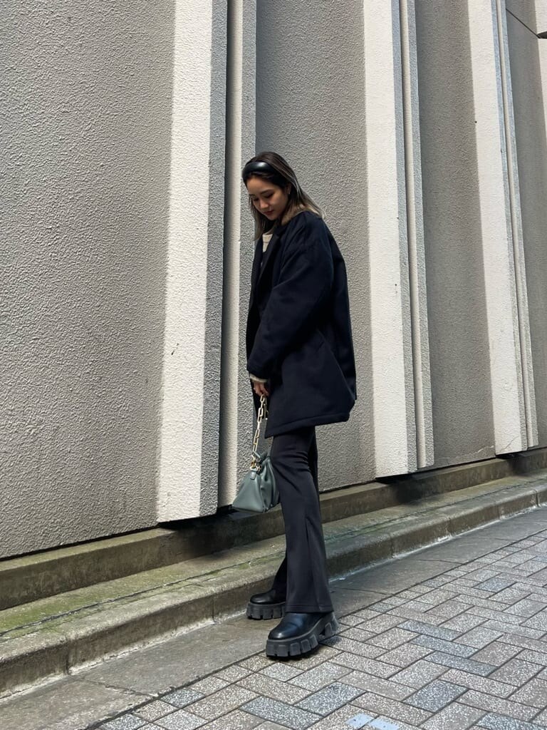 ブラック系のブーツ、ブラック系のその他アウター、グリーン系のショルダーバッグを着用したレディースの秋コーディネートの2枚目の写真