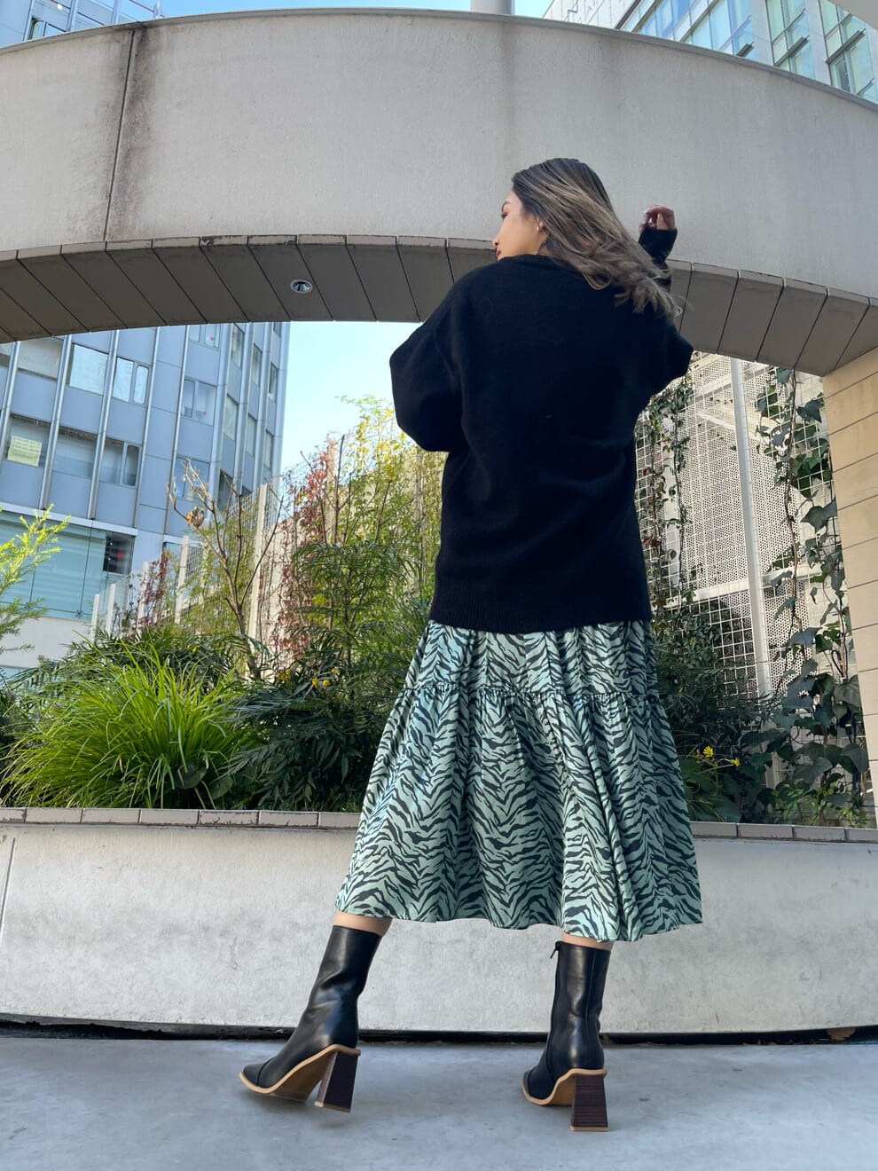 ブラック系のブーツ、グリーン系のワンピース、ブラック系のニット/セーターを着用したレディースの冬コーディネートの2枚目の写真