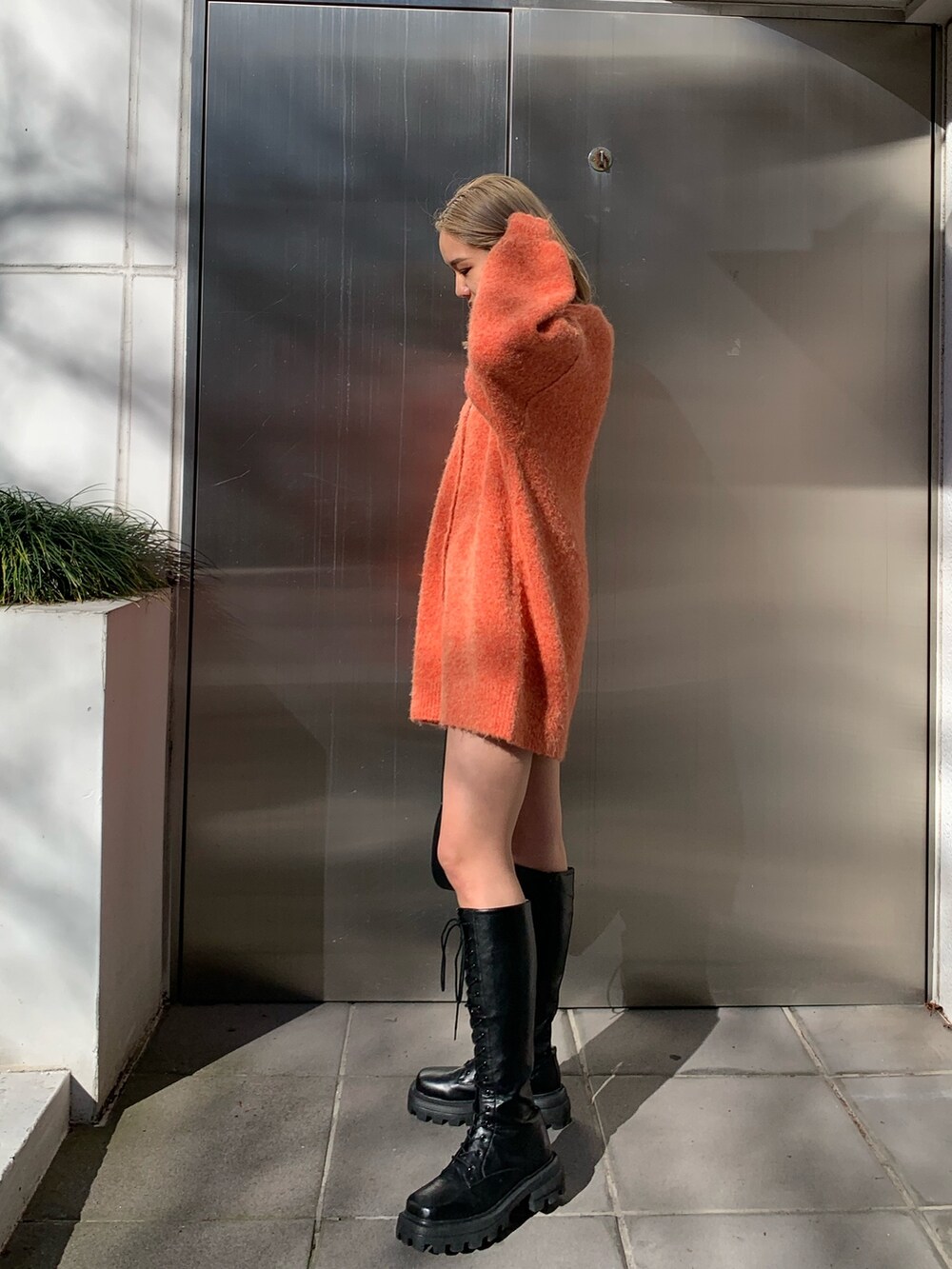 ブラック系のハンドバッグ、オレンジ系のカーディガン/ボレロ、ホワイト系のTシャツ/カットソーを着用したレディースの冬コーディネートの3枚目の写真