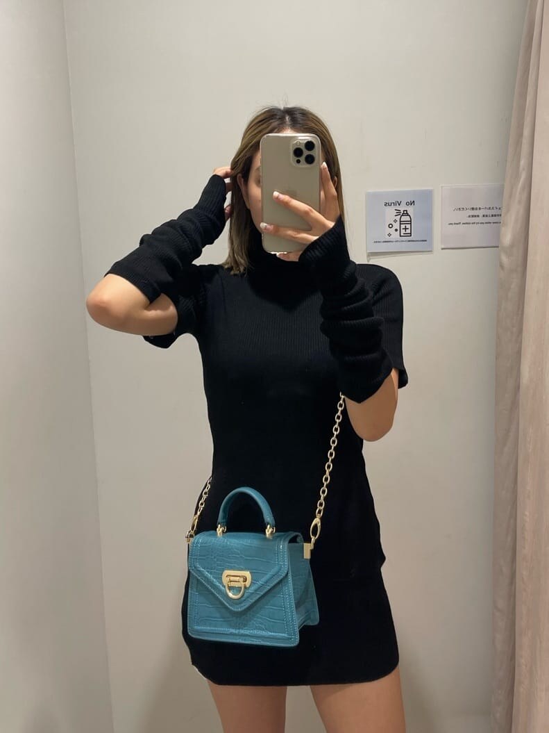 ブラック系のブーツ、ブラック系のワンピース、グリーン系のショルダーバッグを着用したレディースの秋コーディネートの2枚目の写真