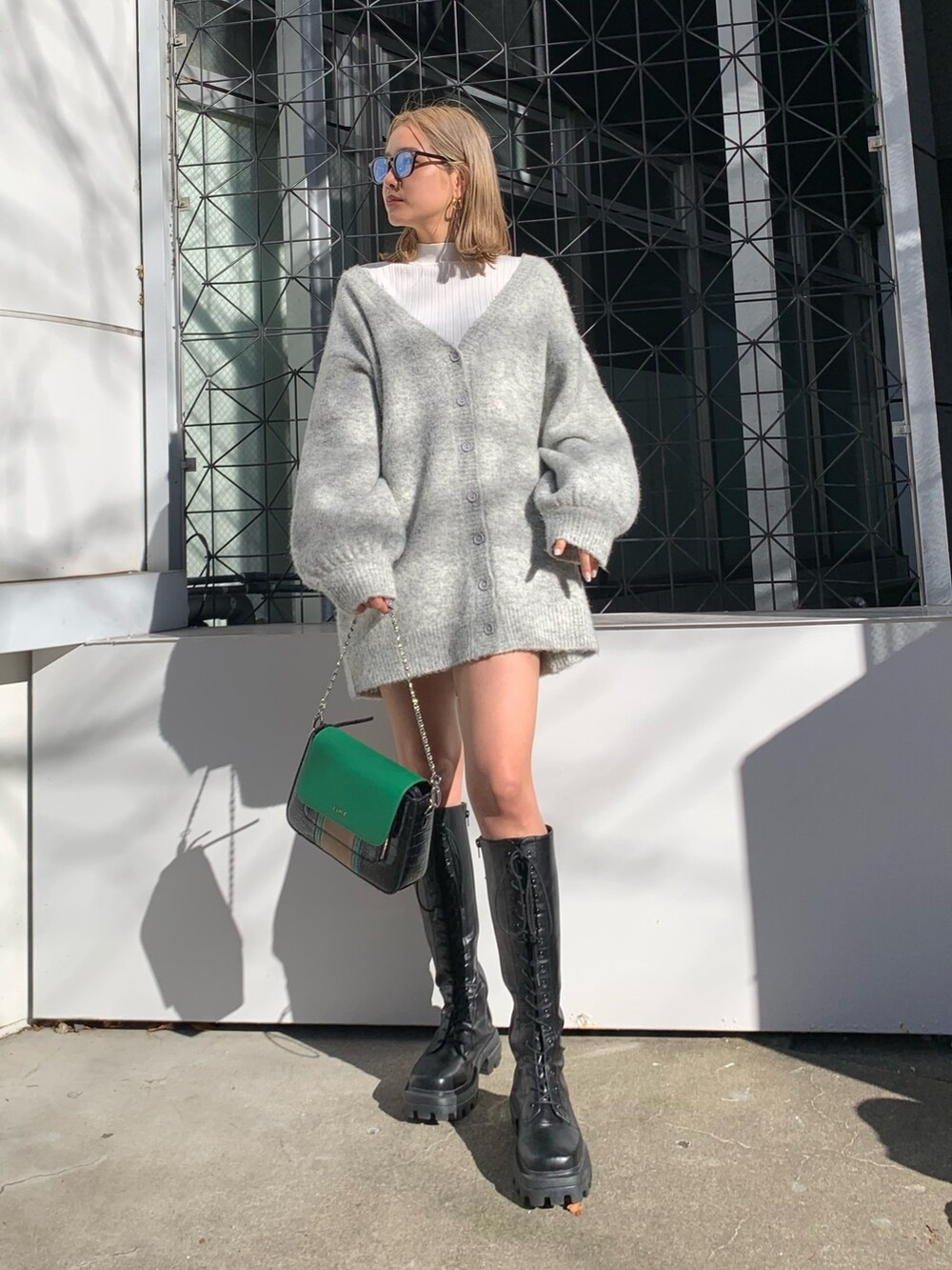 グレー系のカーディガン/ボレロ、ブラック系のブーツ、ホワイト系のTシャツ/カットソーを着用したレディースの冬コーディネートの2枚目の写真