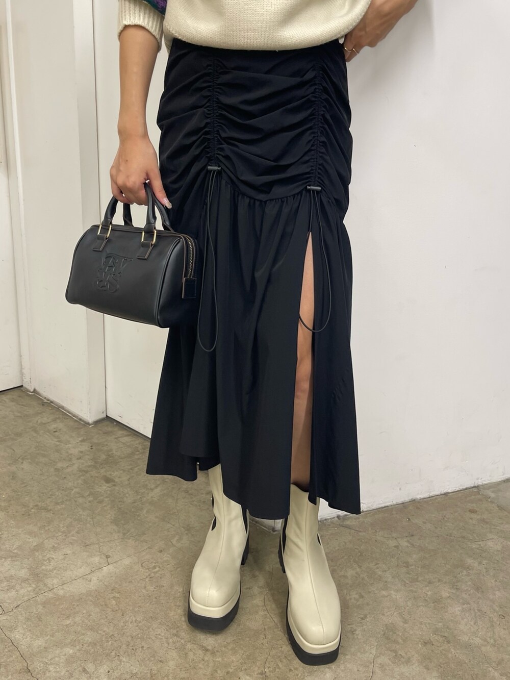 ブラック系のスカート、ホワイト系のブーツ、イエロー系のニット/セーターを着用したレディースの秋コーディネートの9枚目の写真