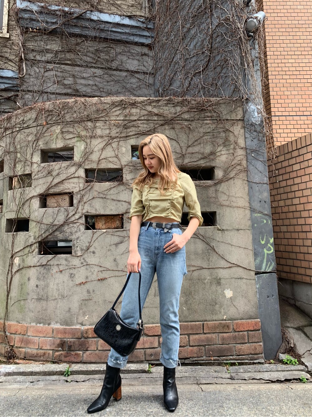 ブルー系のデニムパンツ、グリーン系のシャツ/ブラウス、ブラック系のショルダーバッグを着用したレディースの春コーディネートの2枚目の写真