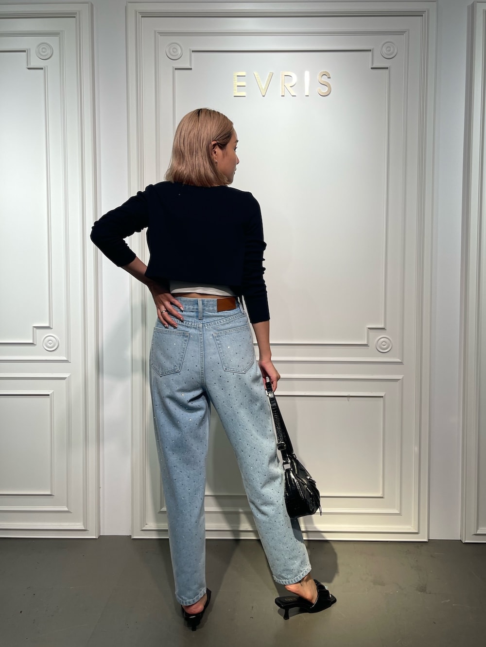 ブラック系のショルダーバッグ、ブルー系のデニムパンツ、ブラック系のサンダルを着用したレディースの夏コーディネートの3枚目の写真