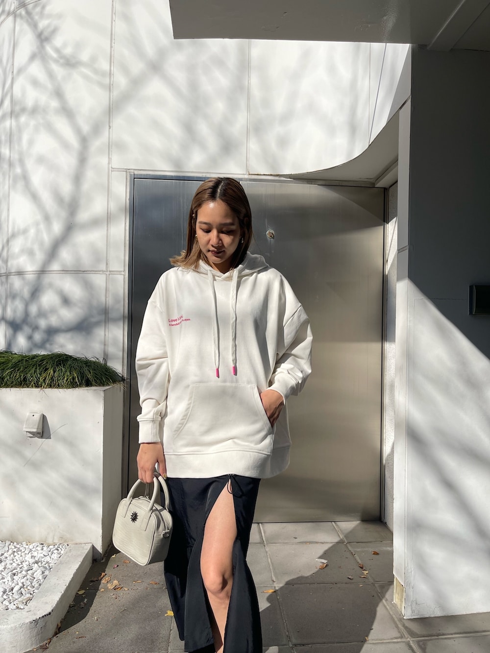 ホワイト系のパーカー、ホワイト系のショルダーバッグ、ブラック系のブーツを着用したレディースの冬コーディネートの3枚目の写真