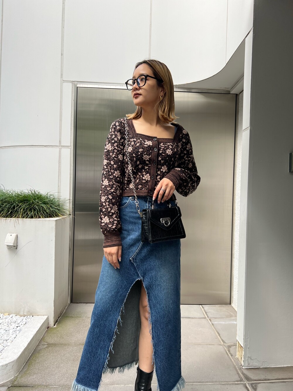 ブルー系のデニムスカート、ブラック系のブーツ、ブラック系のニット/セーターを着用したレディースの秋コーディネートの4枚目の写真