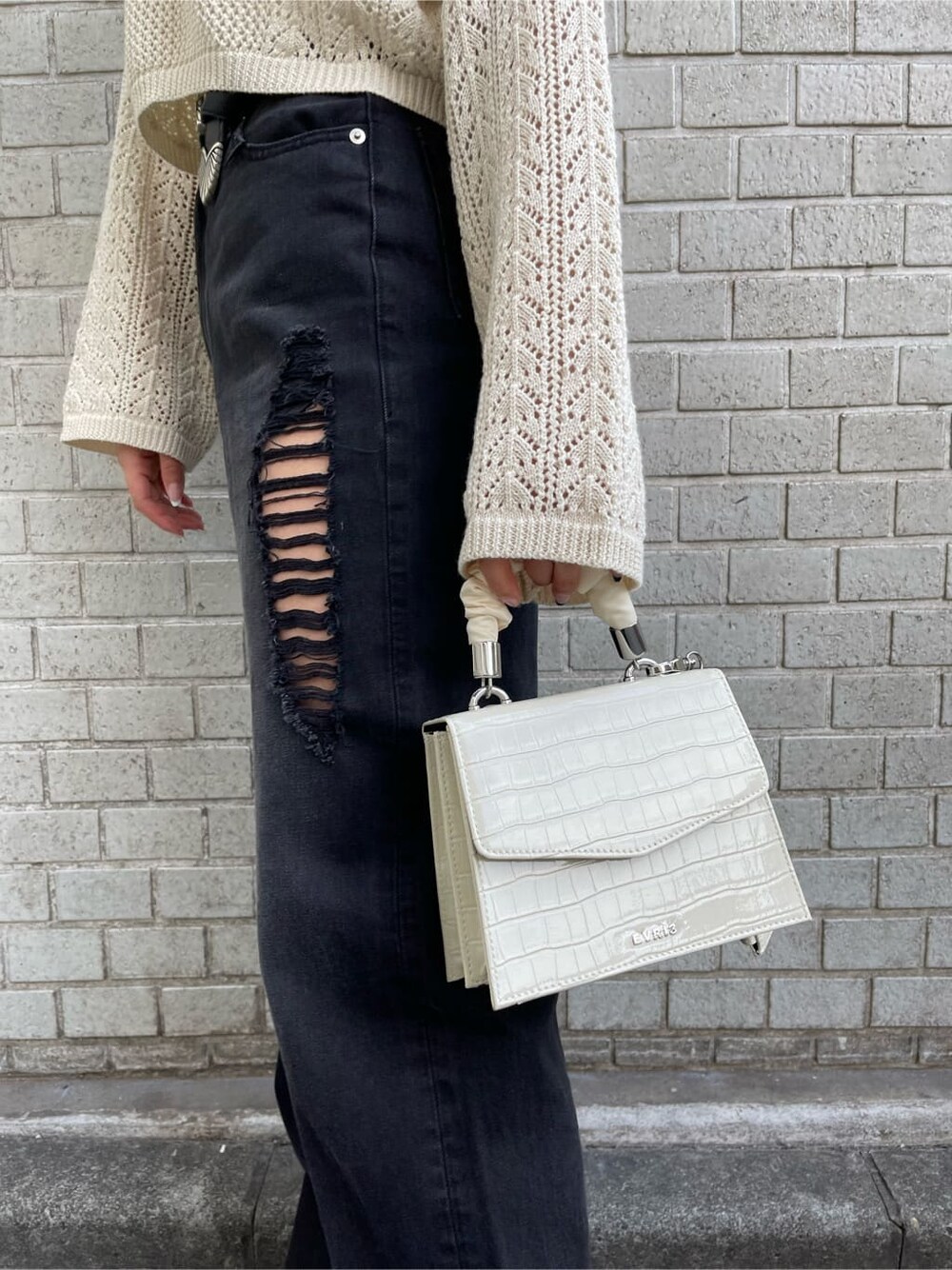 ホワイト系のキャミソール、ブラック系のデニムパンツ、ホワイト系のニット/セーターを着用したレディースの春コーディネートの8枚目の写真