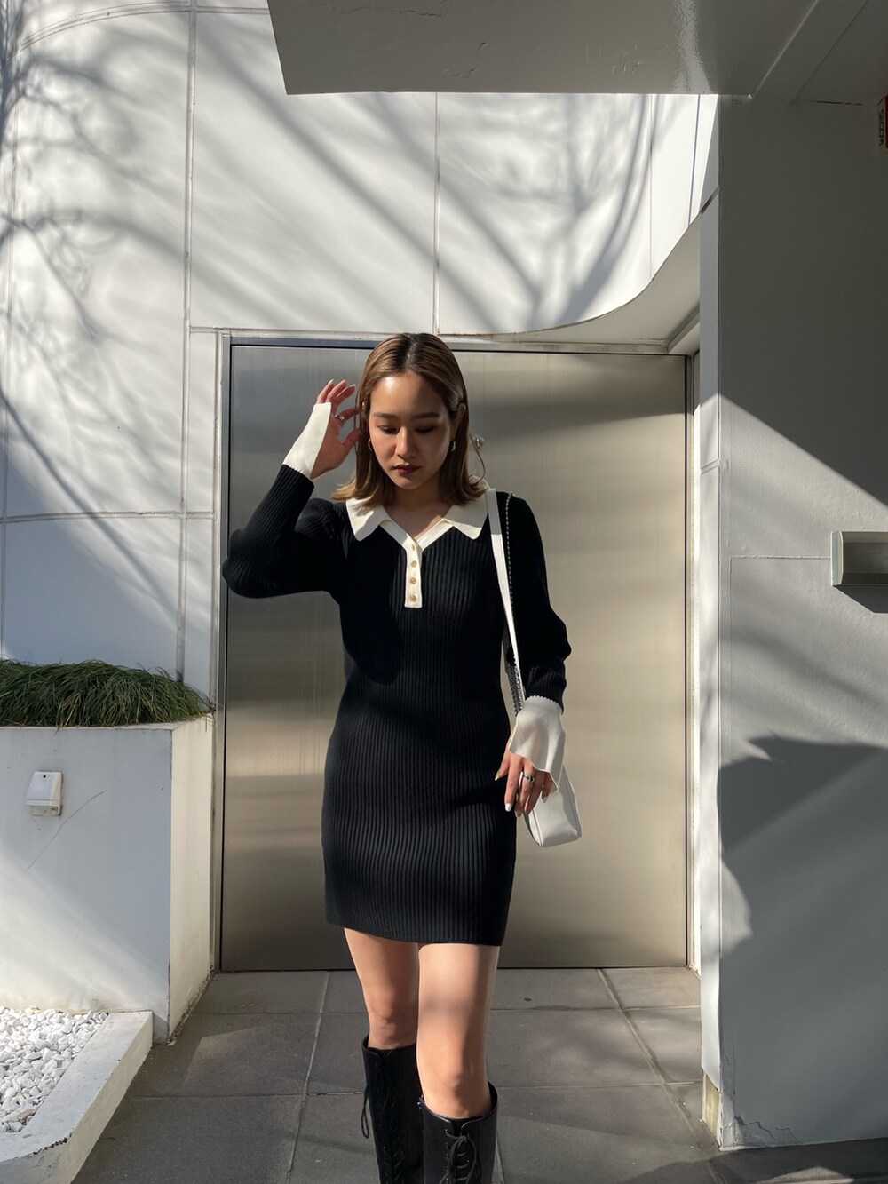 ブラック系のブーツ、ブラック系のワンピース、ホワイト系のショルダーバッグを着用したレディースの冬コーディネートの4枚目の写真