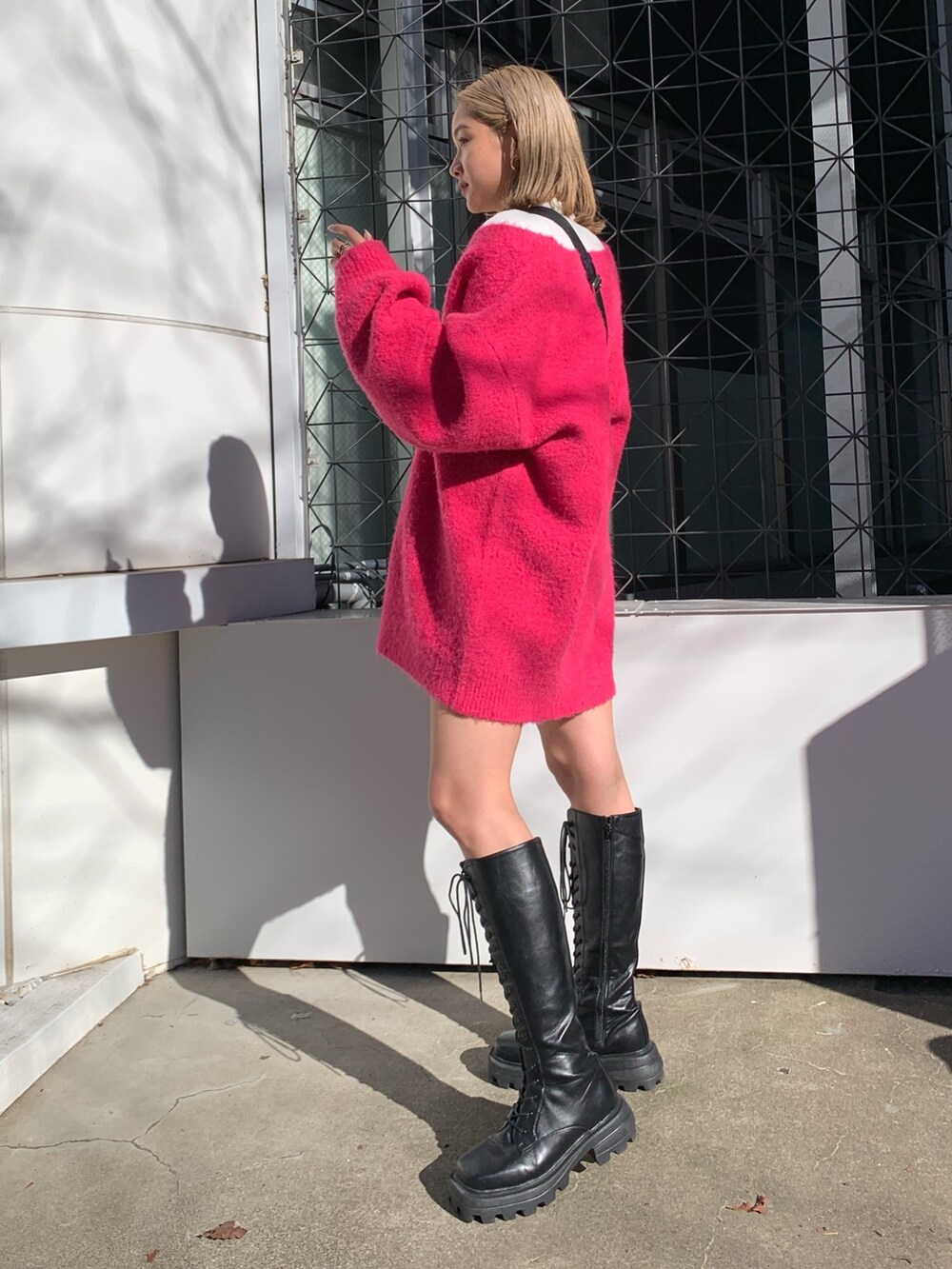 ピンク系のカーディガン/ボレロ、ホワイト系のTシャツ/カットソー、ブラック系のブーツを着用したレディースの冬コーディネートの2枚目の写真