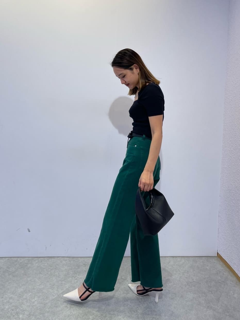 ブラック系のハンドバッグ、ホワイト系のサンダル、グリーン系のデニムパンツを着用したレディースの夏コーディネートの2枚目の写真