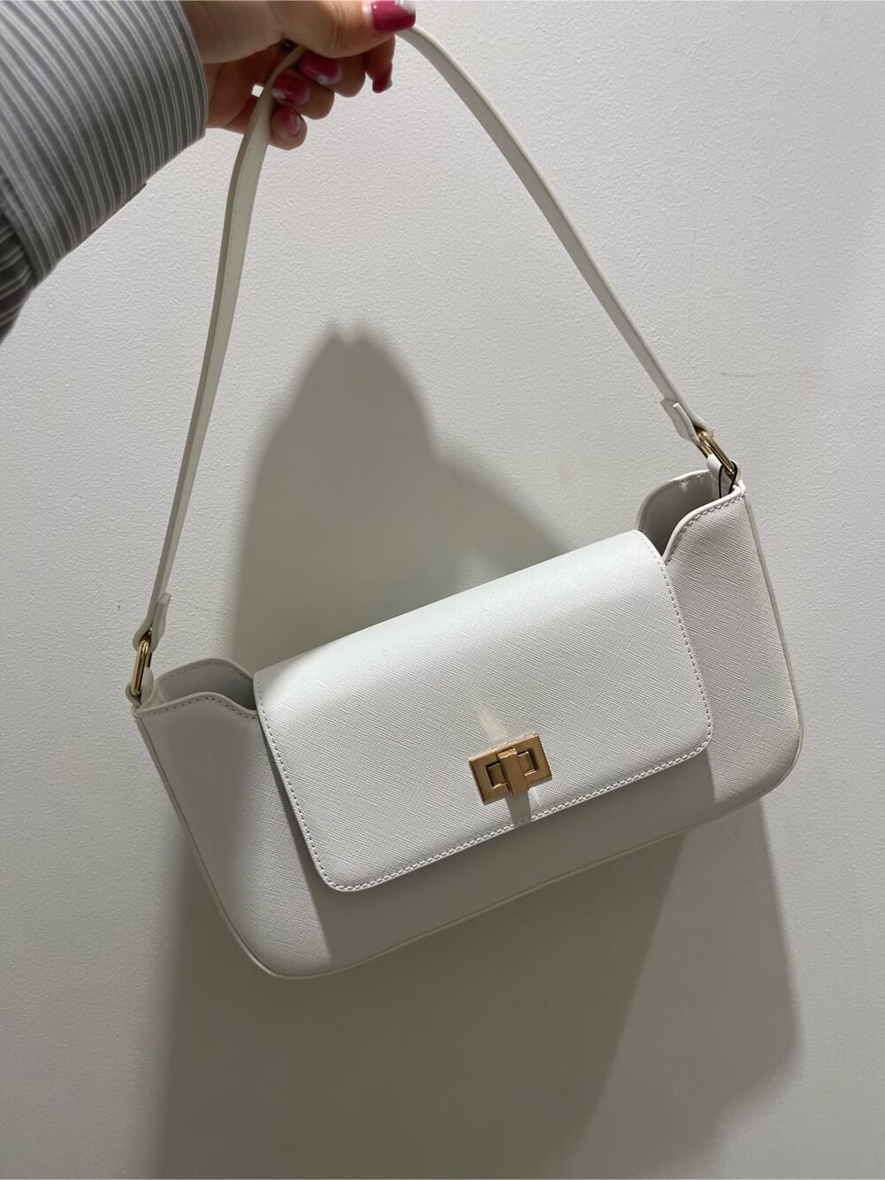 ブラック系のスラックス、ブラック系のワンピース、ホワイト系のショルダーバッグを着用したレディースの春コーディネートの9枚目の写真