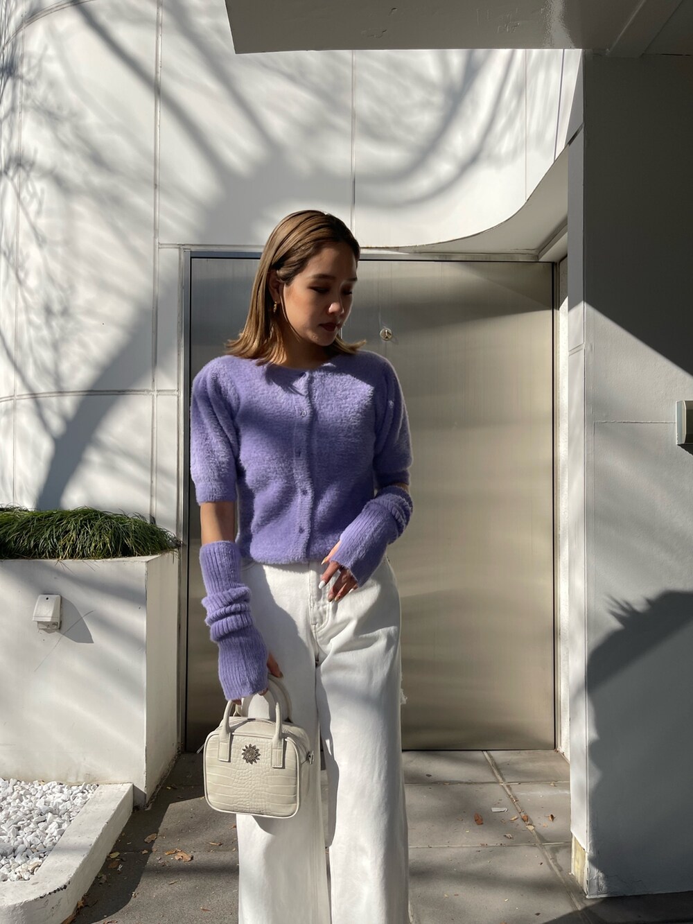 パープル系のニット/セーター、ホワイト系のデニムパンツ、ホワイト系のショルダーバッグを着用したレディースの冬コーディネートの5枚目の写真