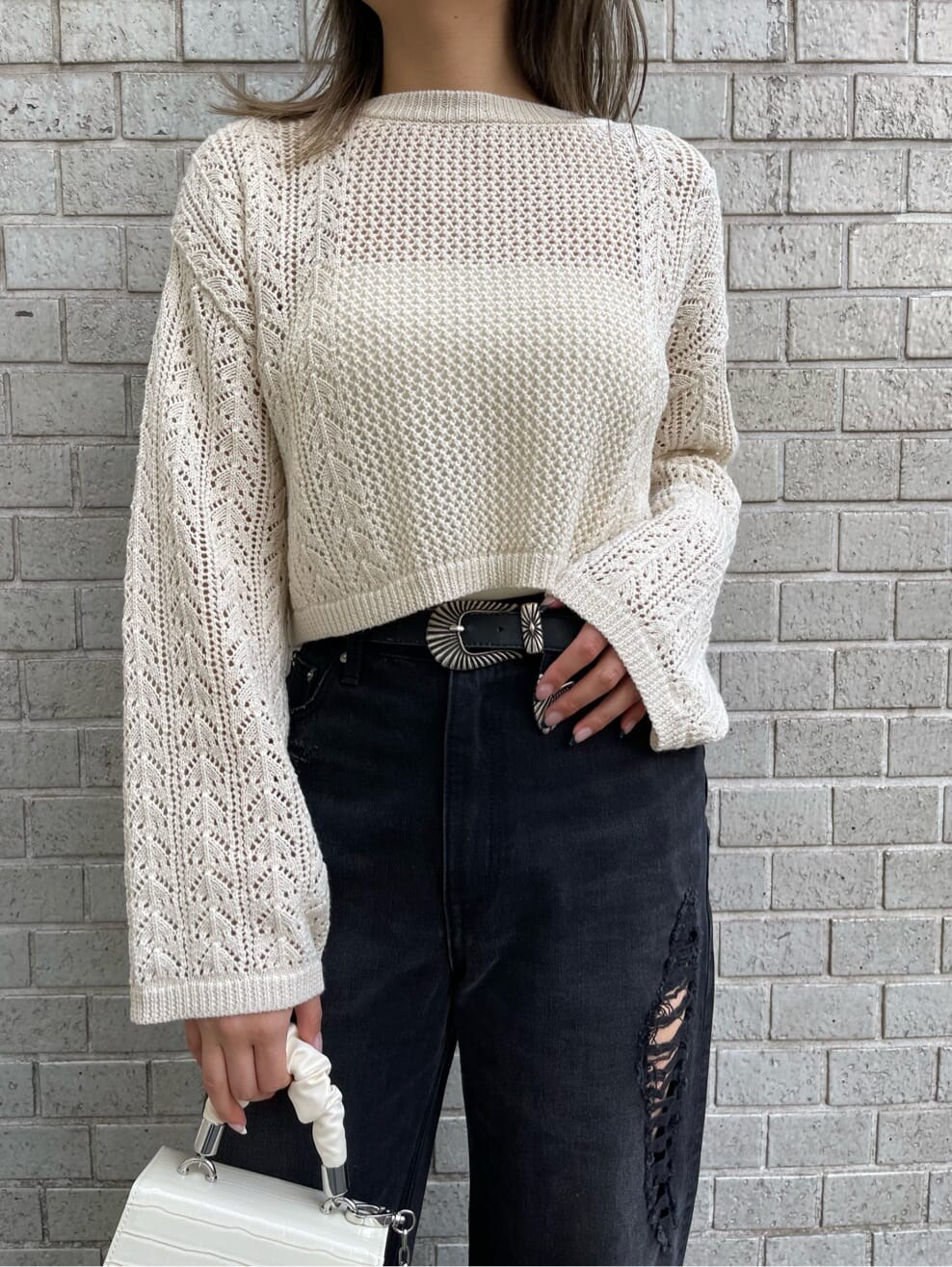 ホワイト系のキャミソール、ブラック系のデニムパンツ、ホワイト系のニット/セーターを着用したレディースの春コーディネートの4枚目の写真