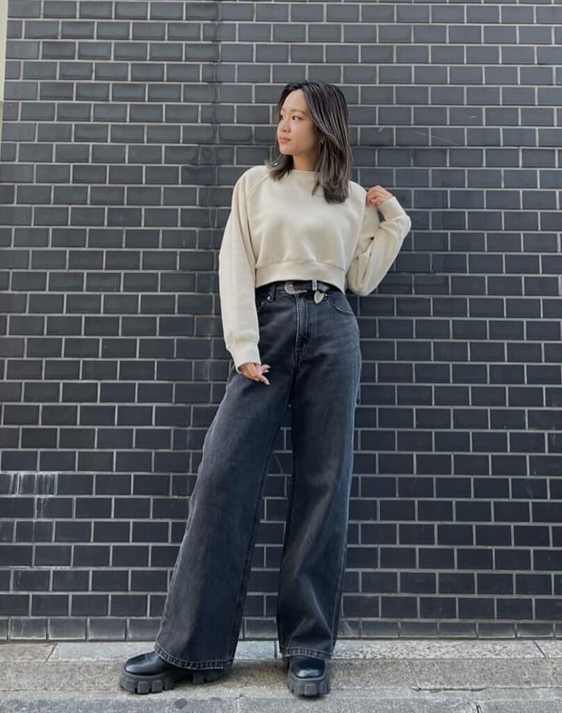 ブラック系のデニムパンツ、ブラック系のブーツ、ホワイト系のスウェットを着用したレディースの冬コーディネートの2枚目の写真