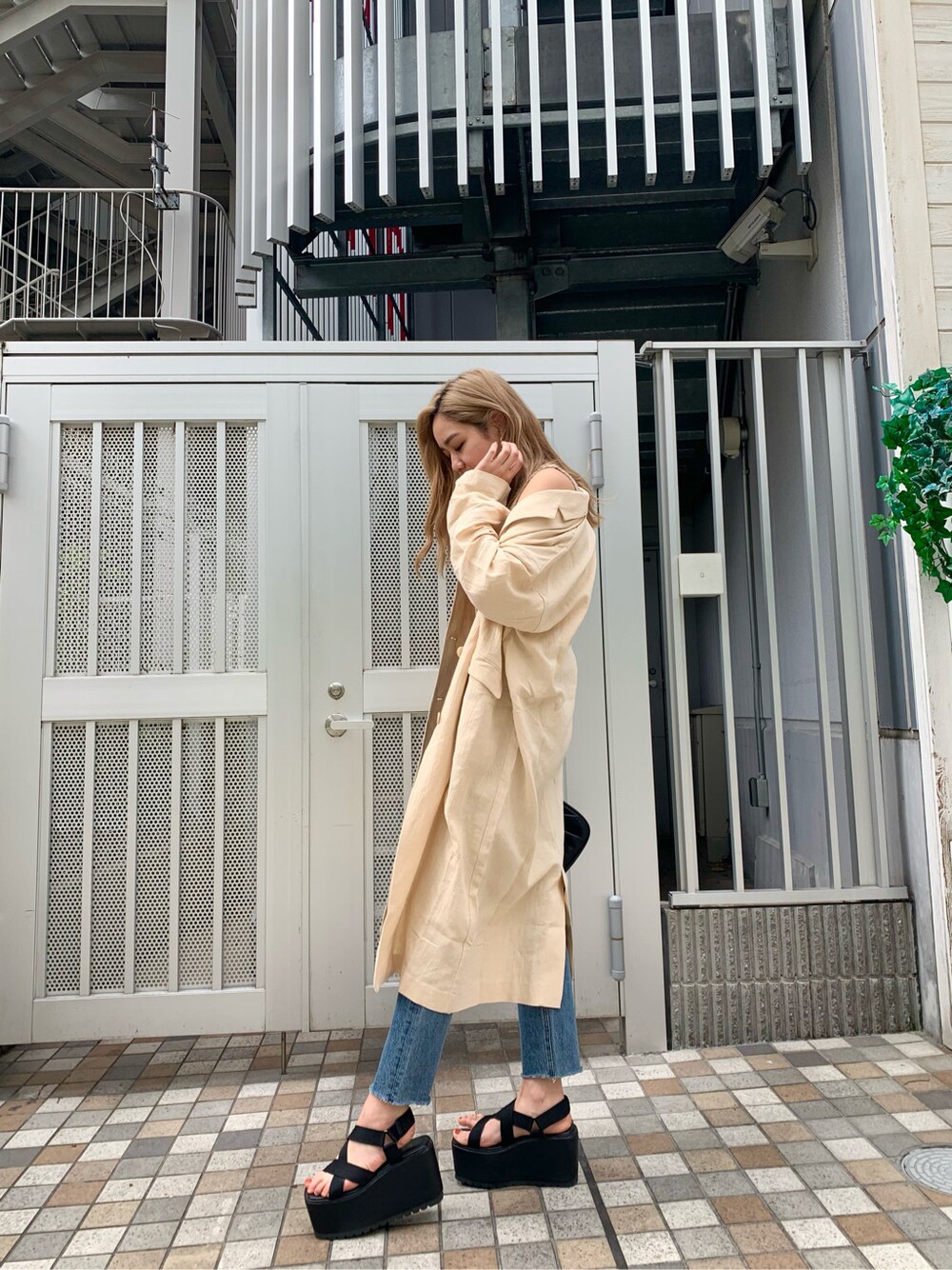 ブルー系のデニムパンツ、ブラック系のサンダル、ベージュ系のチェスターコートを着用したレディースの春コーディネートの3枚目の写真