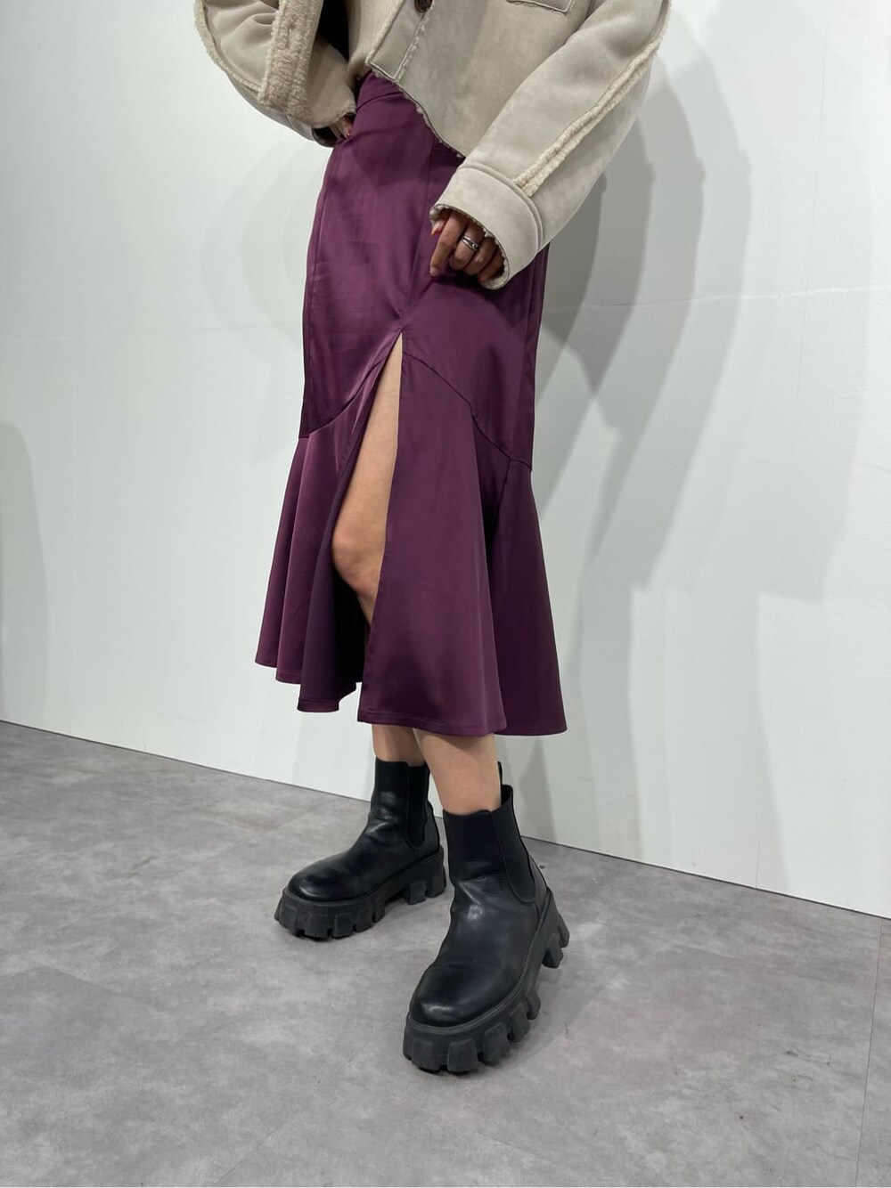 ブラック系のブーツ、ホワイト系のニット/セーター、パープル系のスカートを着用したレディースの秋コーディネートの7枚目の写真