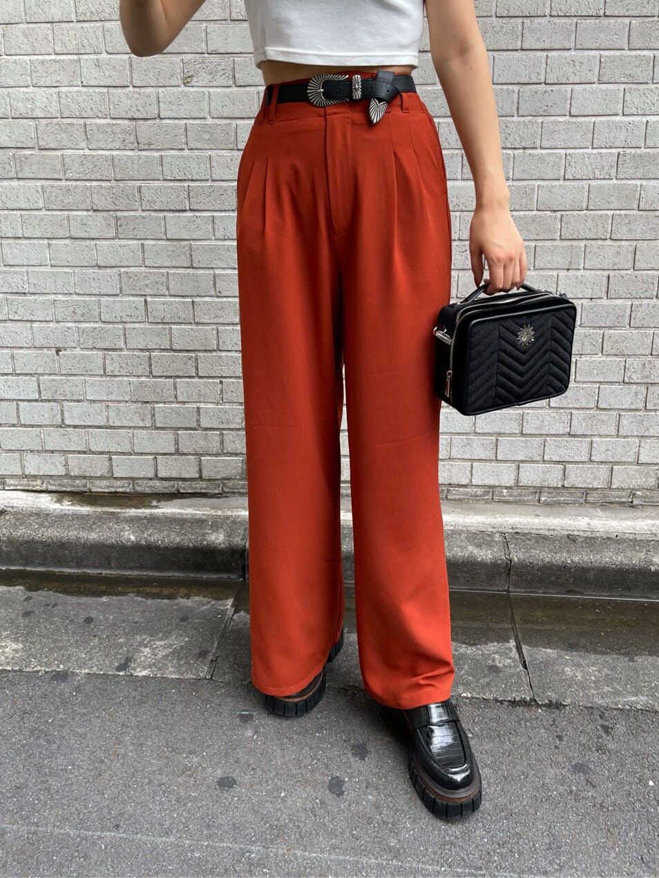 ブラック系のローファー、オレンジ系のその他パンツ、ブラック系のハンドバッグを着用したレディースの夏コーディネートの5枚目の写真