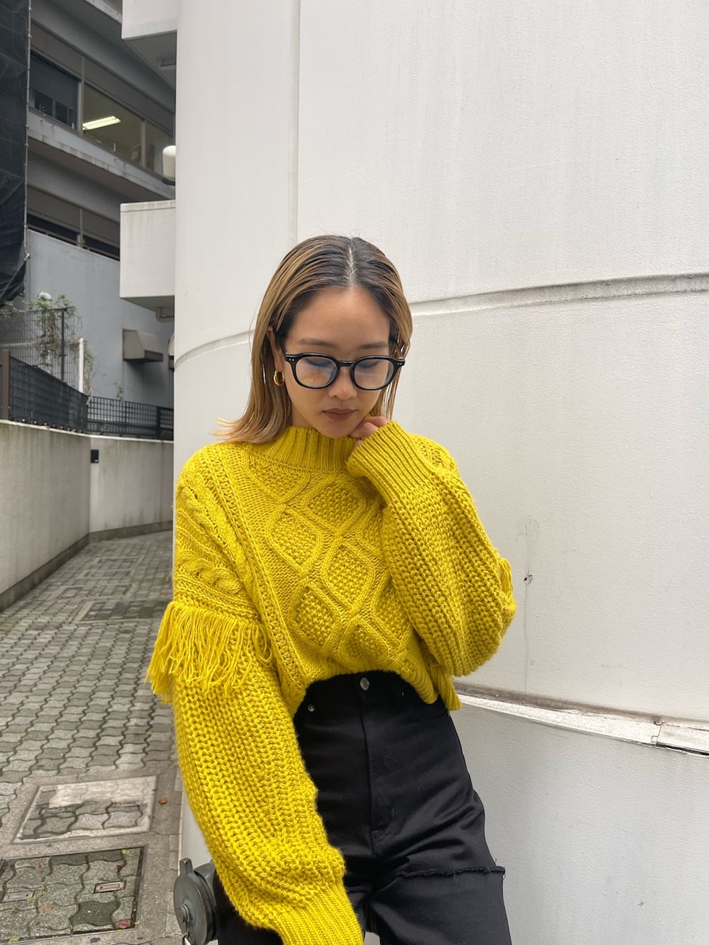 ブラック系のショルダーバッグ、イエロー系のニット/セーター、ブラック系のデニムパンツを着用したレディースの秋コーディネートの7枚目の写真