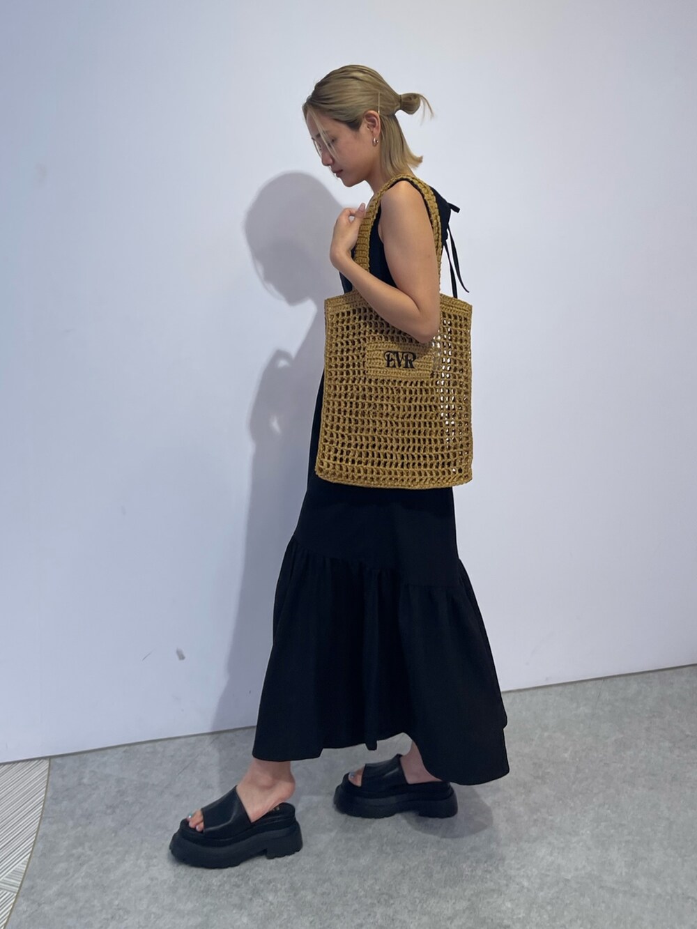 ベージュ系のトートバッグ、ブラック系のワンピース、ブラック系のサンダルを着用したレディースの夏コーディネートの4枚目の写真