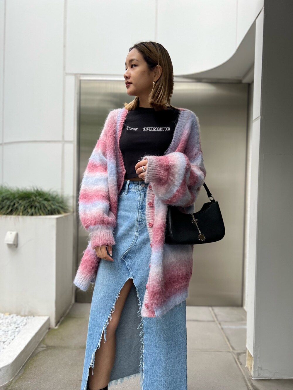 ブラック系のTシャツ/カットソー、ブルー系のデニムスカート、ピンク系のカーディガン/ボレロを着用したレディースの秋コーディネートの6枚目の写真