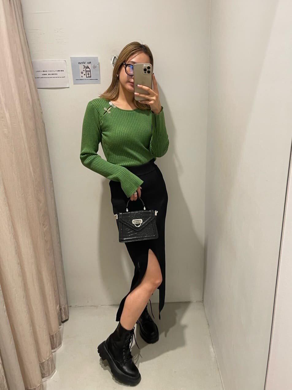 ブラック系のブーツ、グリーン系のニット/セーター、ブラック系のハンドバッグを着用したレディースの秋コーディネートの3枚目の写真