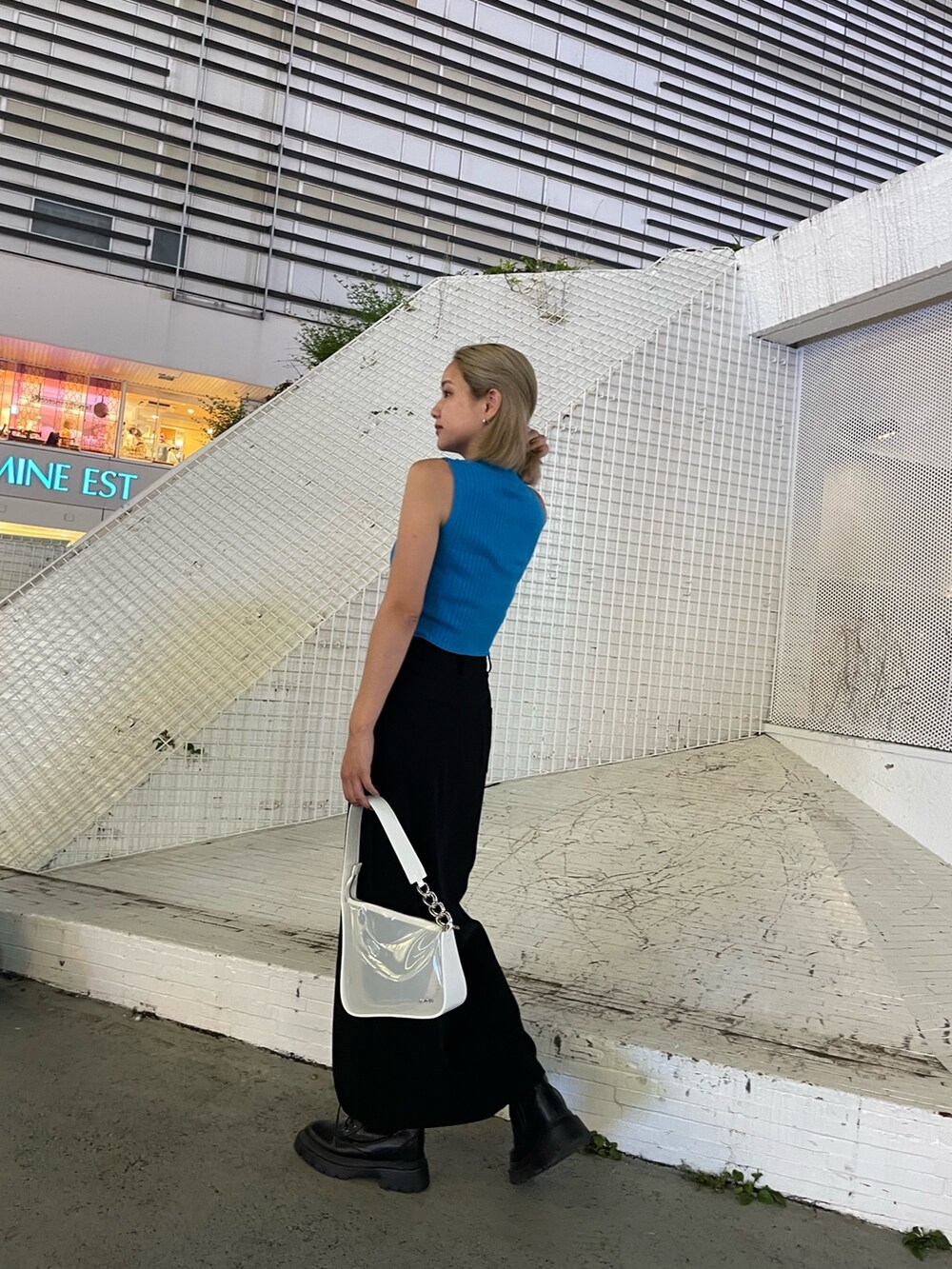 ブラック系のブーツ、ホワイト系のハンドバッグ、ブルー系のタンクトップを着用したレディースの夏コーディネートの3枚目の写真