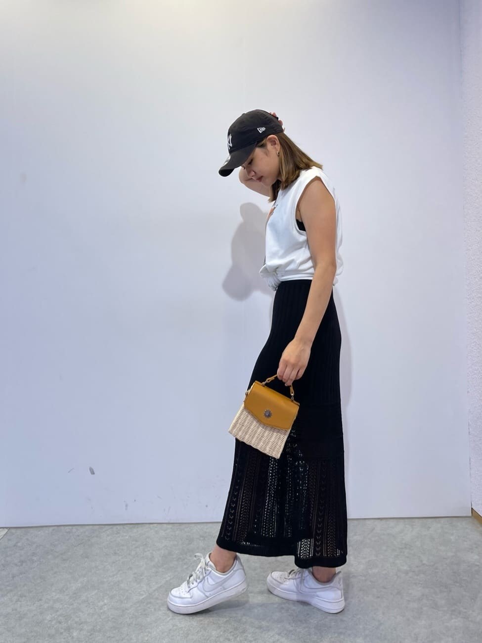 ホワイト系のTシャツ/カットソー、ブラック系のスカート、ベージュ系のショルダーバッグを着用したレディースの夏コーディネートの3枚目の写真