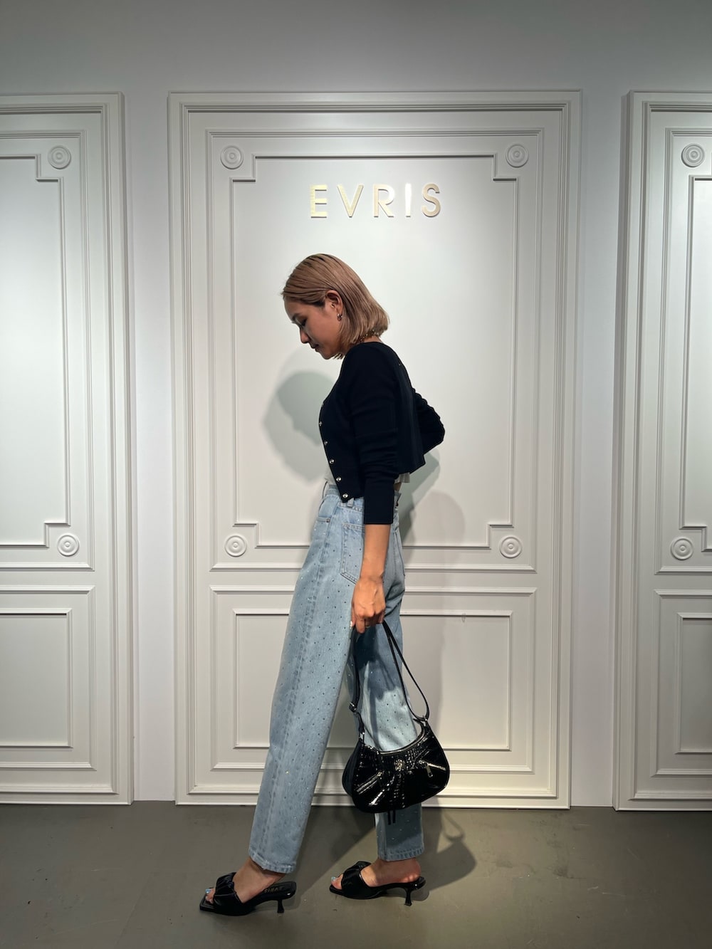 ブラック系のショルダーバッグ、ブルー系のデニムパンツ、ブラック系のサンダルを着用したレディースの夏コーディネートの2枚目の写真