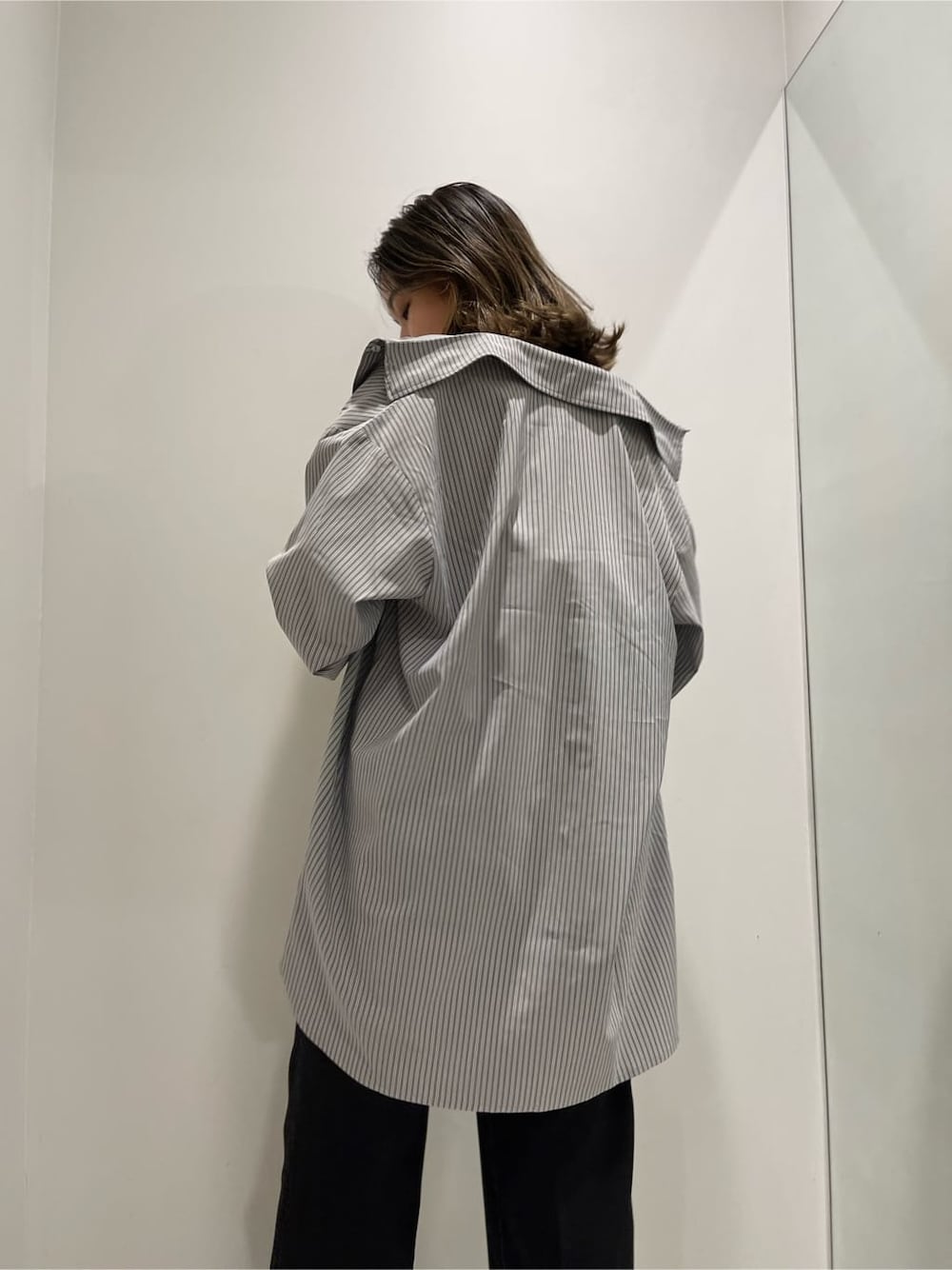 ブラック系のスラックス、ブラック系のワンピース、ホワイト系のショルダーバッグを着用したレディースの春コーディネートの6枚目の写真