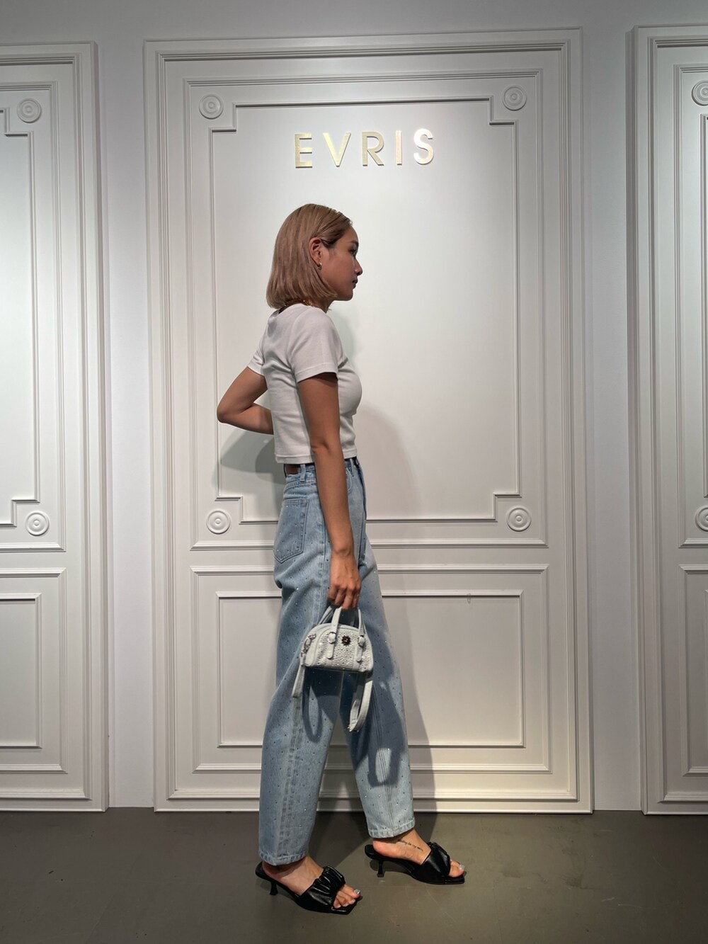 ブルー系のデニムパンツ、ブラック系のサンダル、ホワイト系のTシャツ/カットソーを着用したレディースの夏コーディネートの4枚目の写真