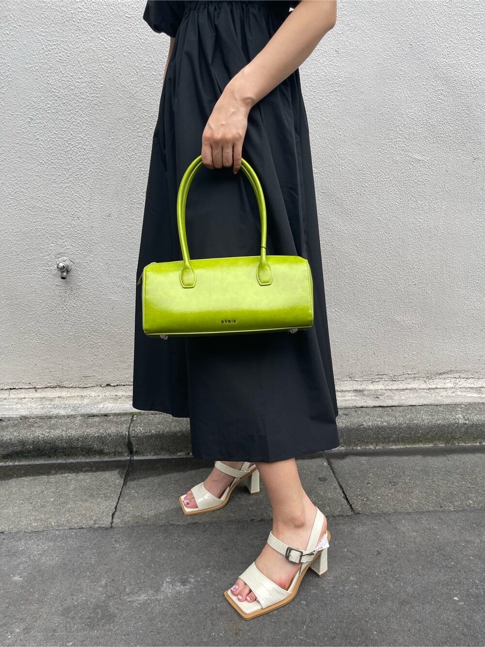 グリーン系のボストンバッグ、ブラック系のワンピース、ホワイト系のサンダルを着用したレディースの春コーディネートの7枚目の写真