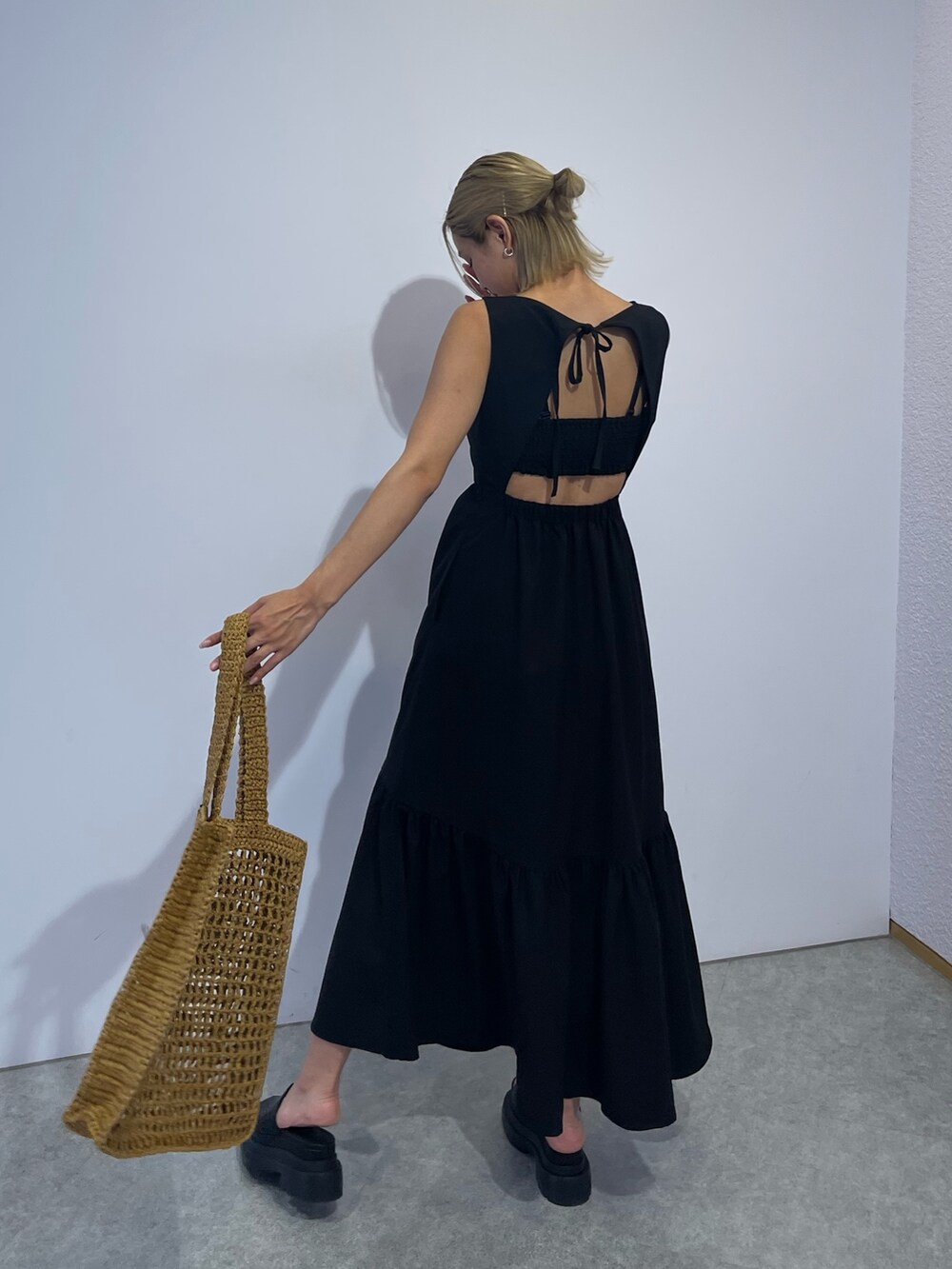 ベージュ系のトートバッグ、ブラック系のワンピース、ブラック系のサンダルを着用したレディースの夏コーディネートの5枚目の写真