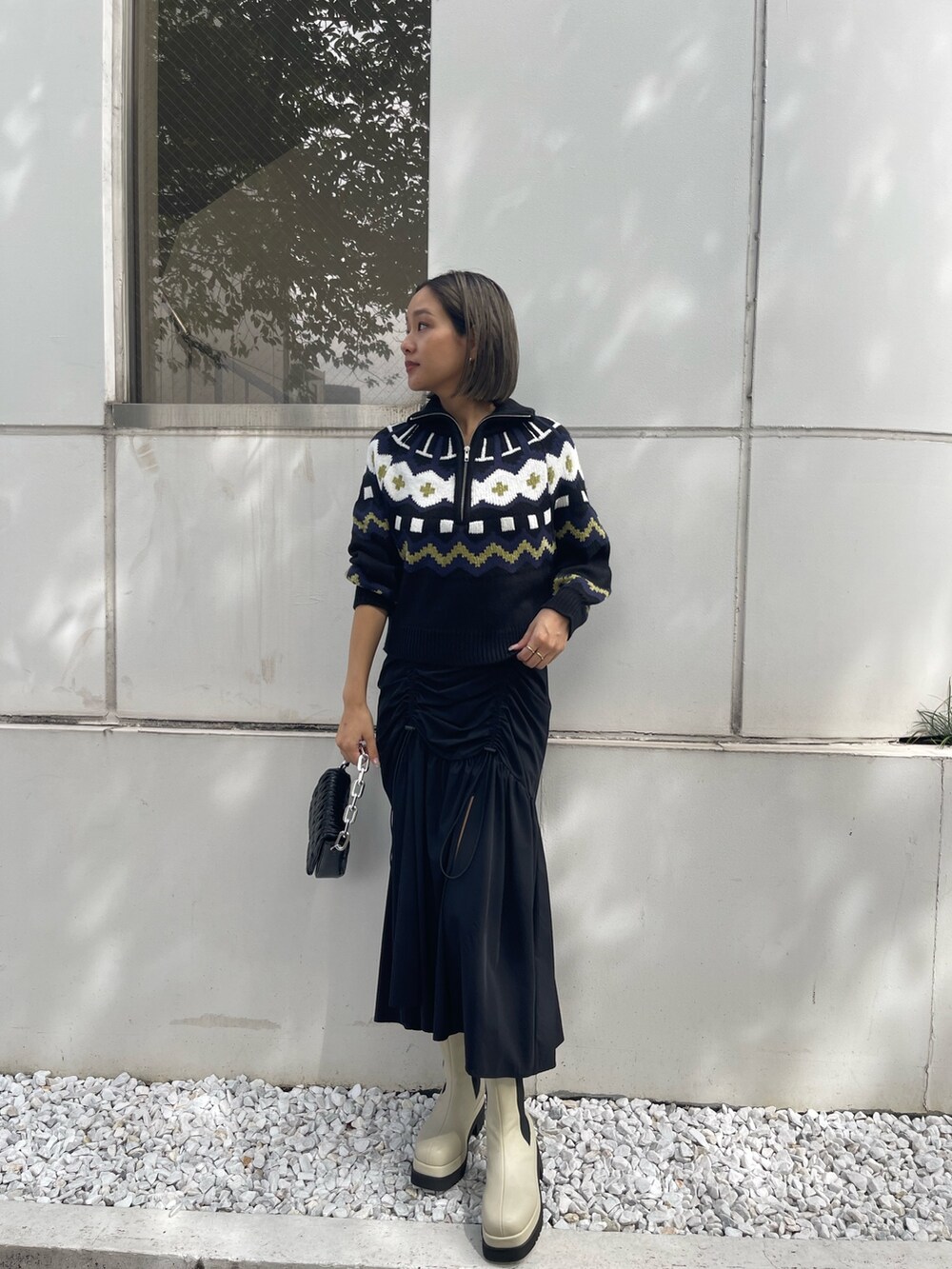 ブラック系のスカート、ホワイト系のブーツ、ブラック系のニット/セーターを着用したレディースの秋コーディネートの4枚目の写真