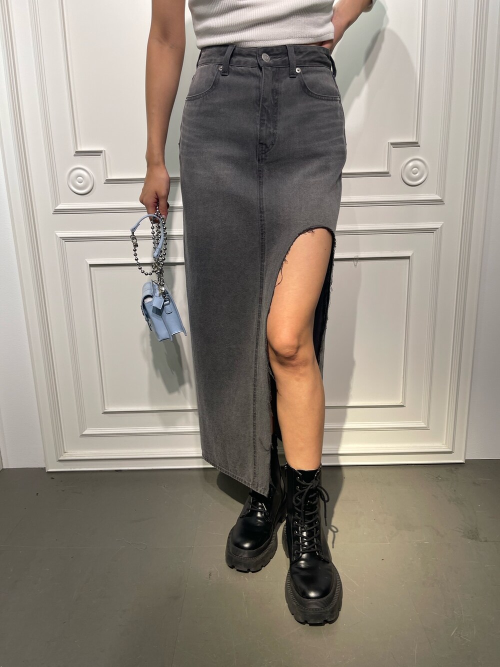 ブラック系のデニムスカート、ブラック系のブーツ、ホワイト系のTシャツ/カットソーを着用したレディースの夏コーディネートの6枚目の写真