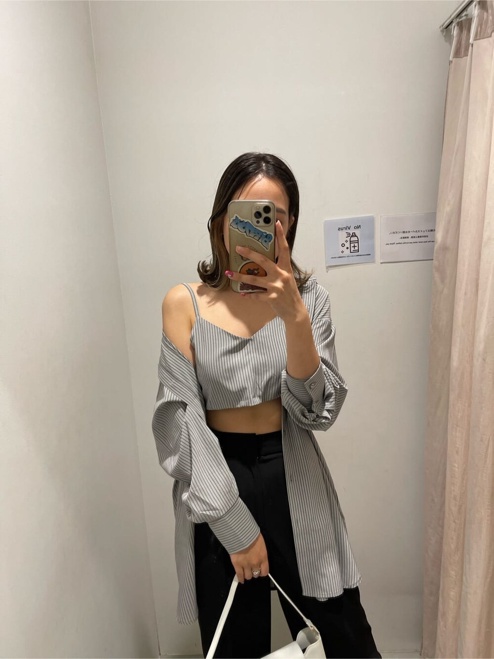 ブラック系のスラックス、ブラック系のワンピース、ホワイト系のショルダーバッグを着用したレディースの春コーディネートの2枚目の写真