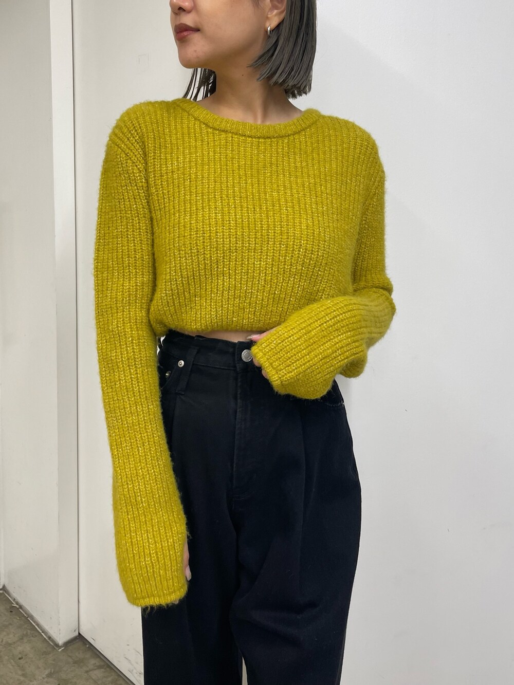 イエロー系のニット/セーター、ブラック系のデニムパンツ、ベージュ系のスリッポンを着用したレディースの秋コーディネートの5枚目の写真