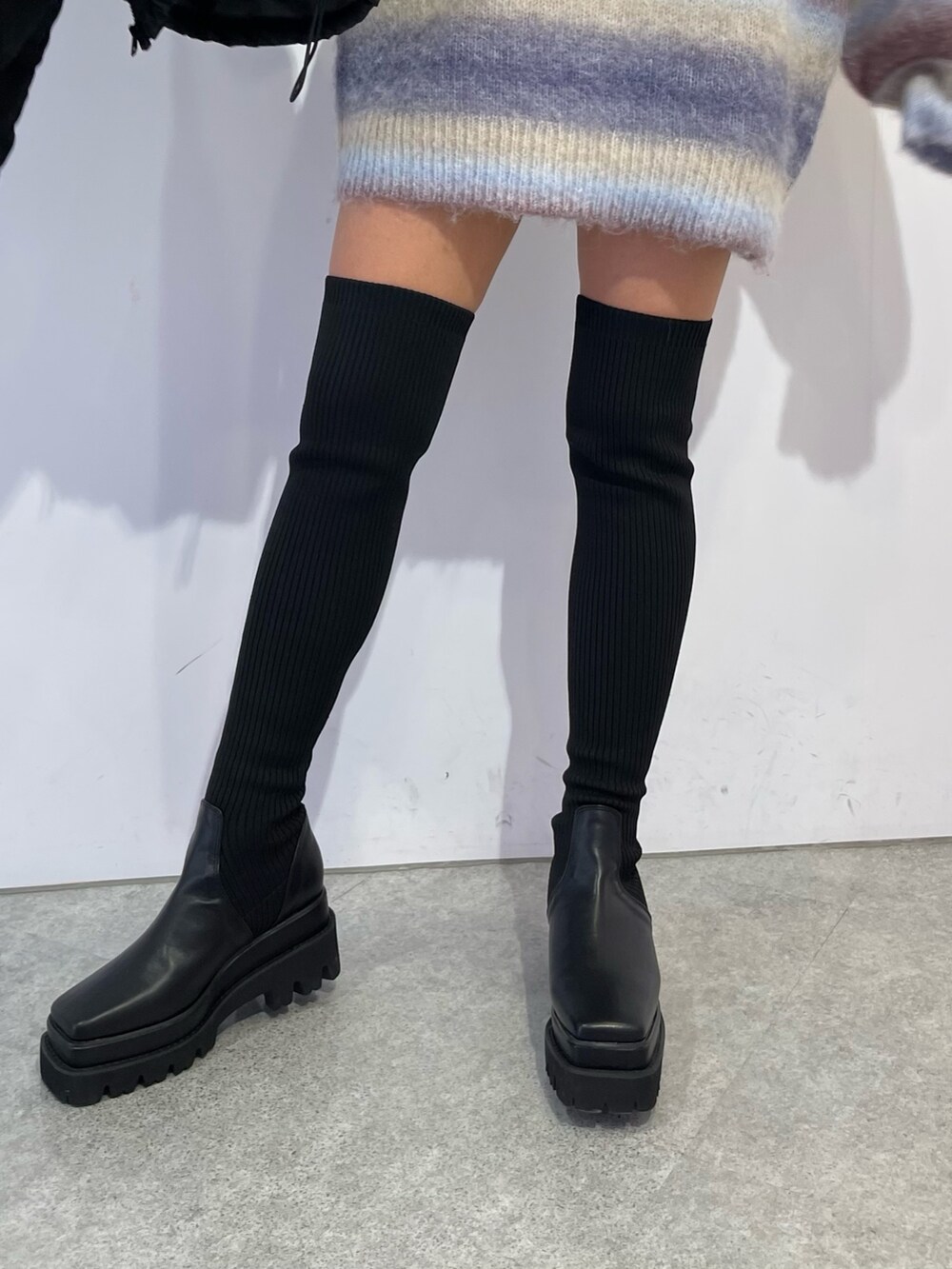 パープル系のニット/セーター、ブラック系のブーツ、ブラック系のダウンジャケット/コートを着用したレディースの冬コーディネートの9枚目の写真