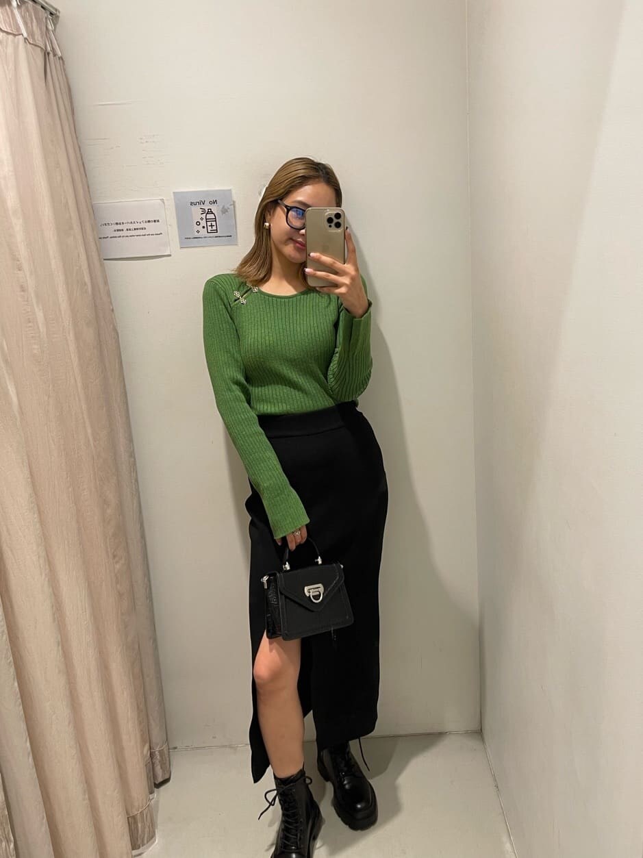 ブラック系のブーツ、グリーン系のニット/セーター、ブラック系のハンドバッグを着用したレディースの秋コーディネートの2枚目の写真