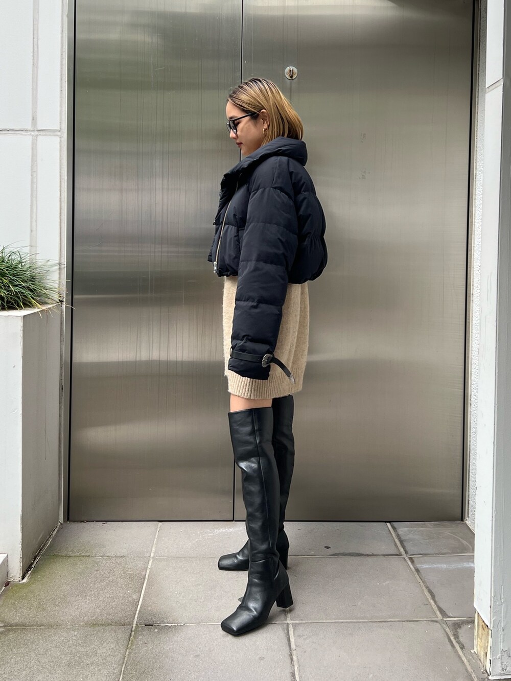 ベージュ系のワンピース、ブラック系のダウンジャケット/コート、ブラック系のブーツを着用したレディースの秋コーディネートの2枚目の写真