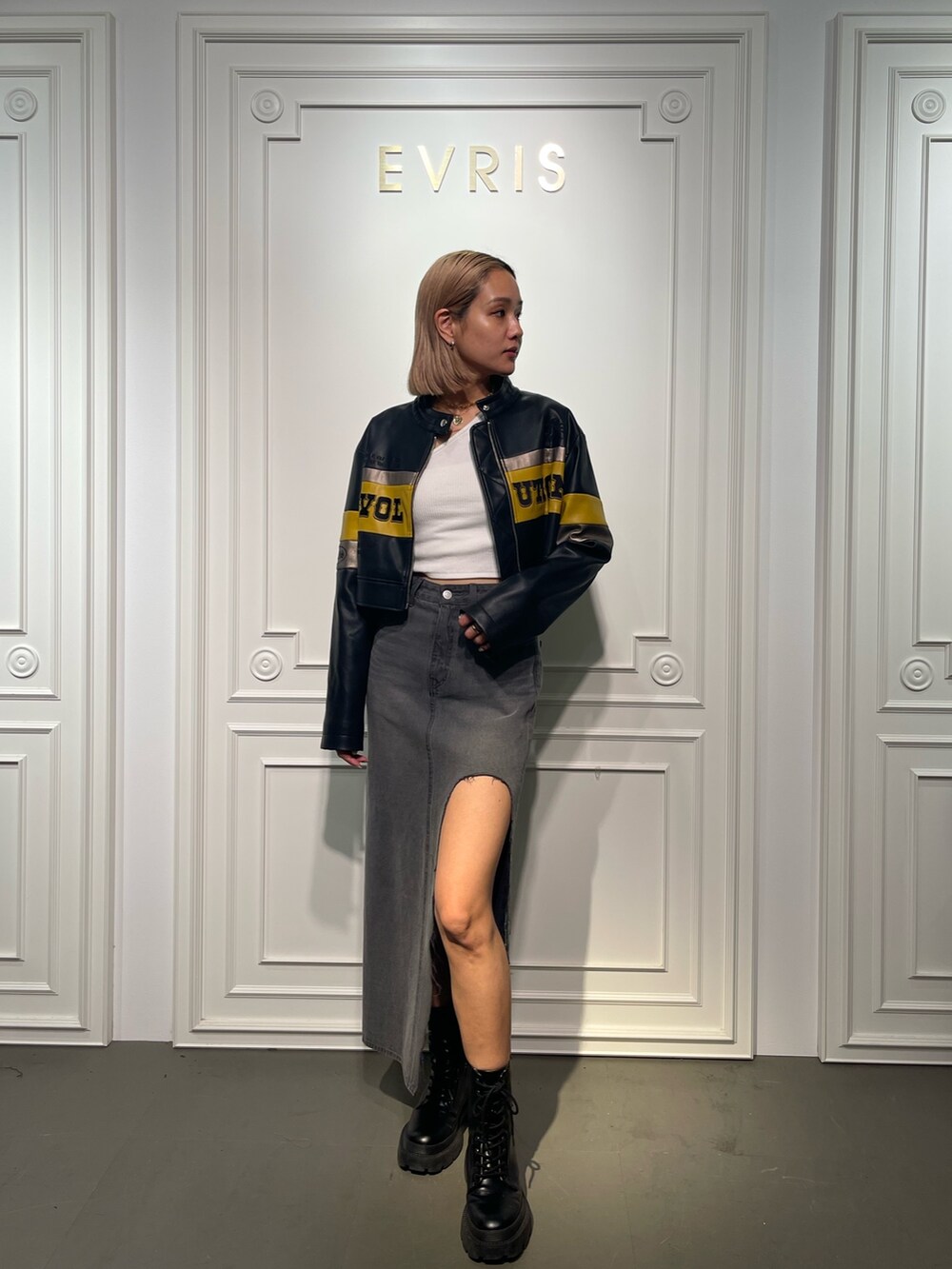 ブラック系のデニムスカート、ブラック系のブーツ、ホワイト系のTシャツ/カットソーを着用したレディースの夏コーディネートの5枚目の写真