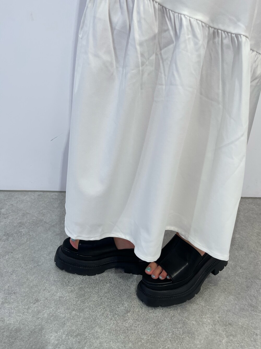 ホワイト系のワンピース、ブラック系のハンドバッグ、ブラック系のサンダルを着用したレディースの夏コーディネートの7枚目の写真