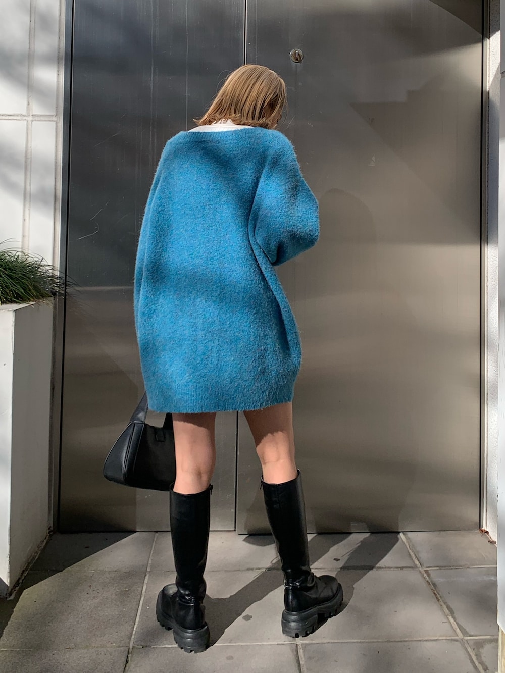 ブラック系のハンドバッグ、ブルー系のカーディガン/ボレロ、ホワイト系のTシャツ/カットソーを着用したレディースの冬コーディネートの3枚目の写真