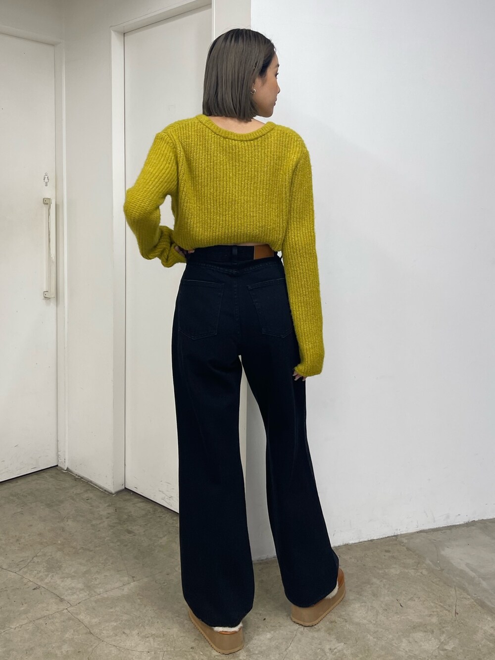 イエロー系のニット/セーター、ブラック系のデニムパンツ、ベージュ系のスリッポンを着用したレディースの秋コーディネートの4枚目の写真